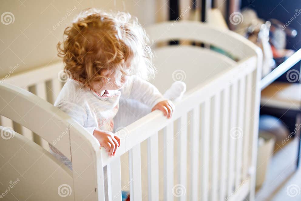 Cute Little Baby Girl Lying in Cot after Sleeping. Healthy Happy Child in Bed Climbing Out Stock