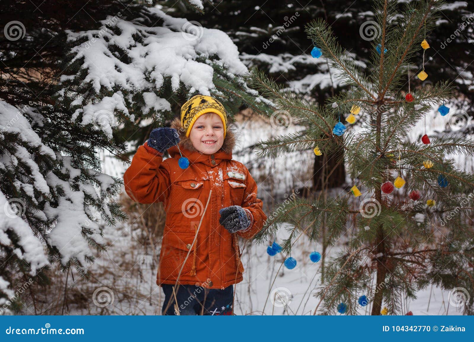 Cute little boy playing with snow in winter snowy forest