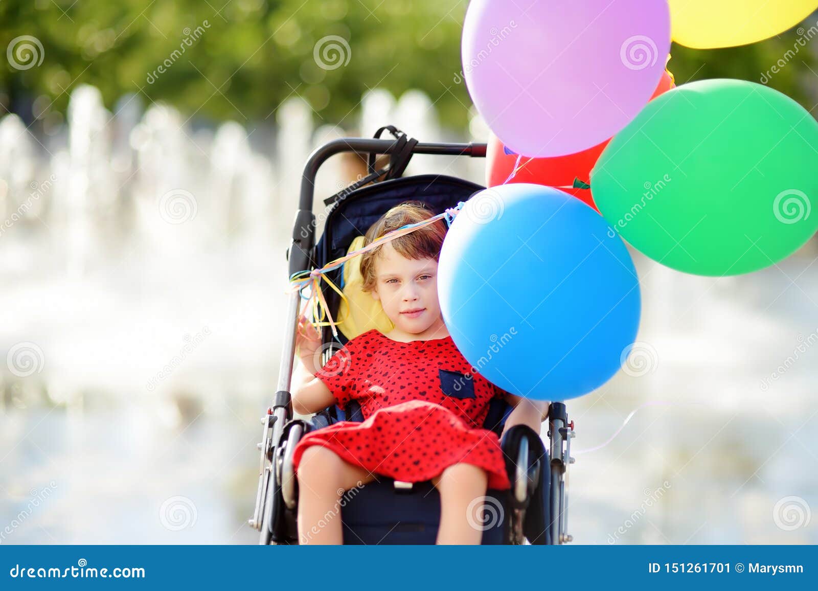 cute little disabled girl in a wheelchair celebrate birthday or walking in the park summer. child cerebral palsy. inclusion