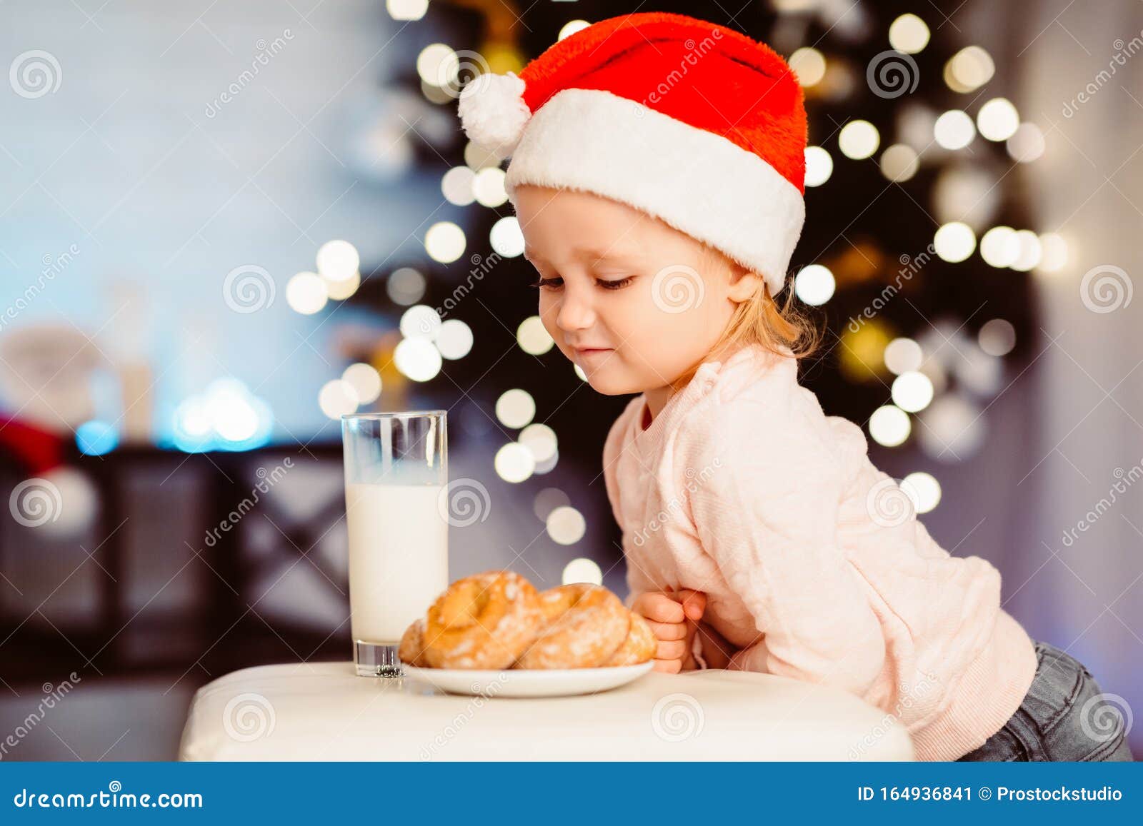 Cute Little Girl Looking at Treats for Santa Near Christmas Tree Stock ...