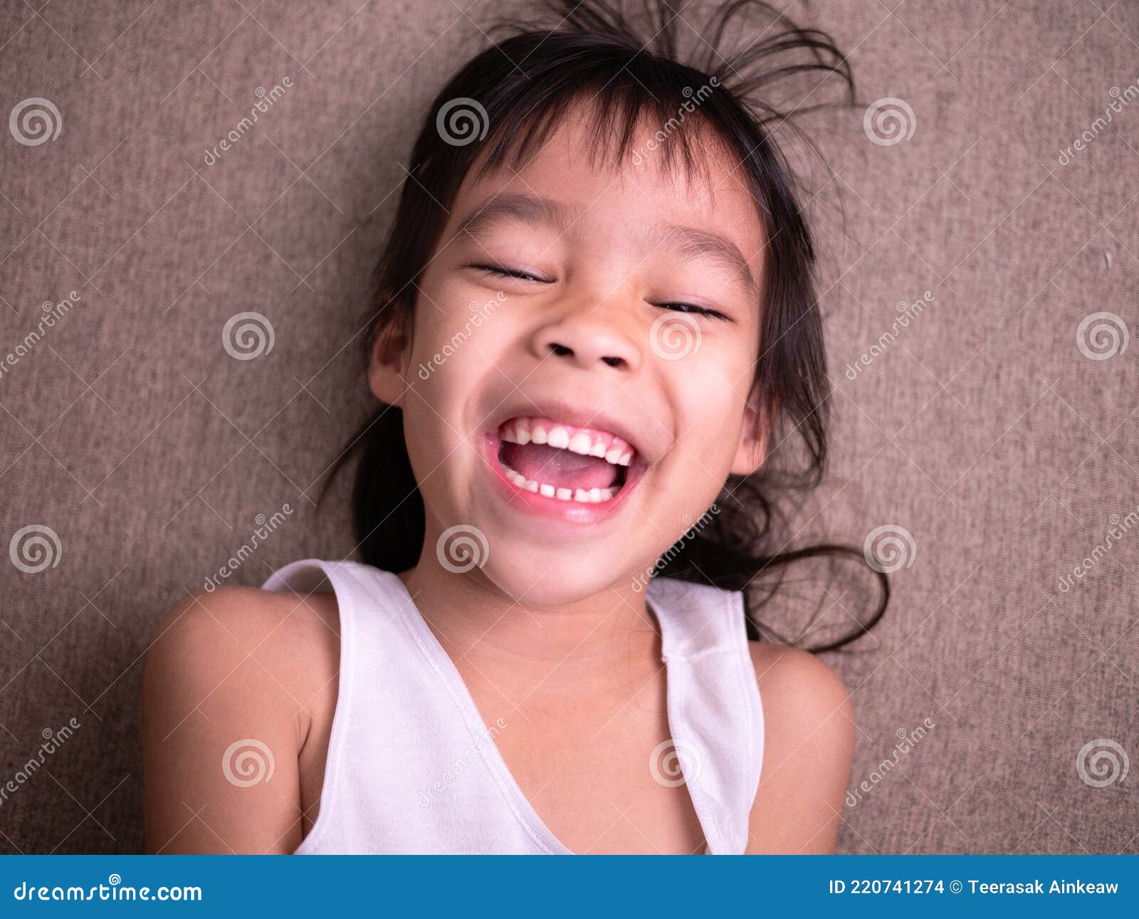 Cute Little Girl Lying on Sofa in the Living Room, Looking at Camera ...