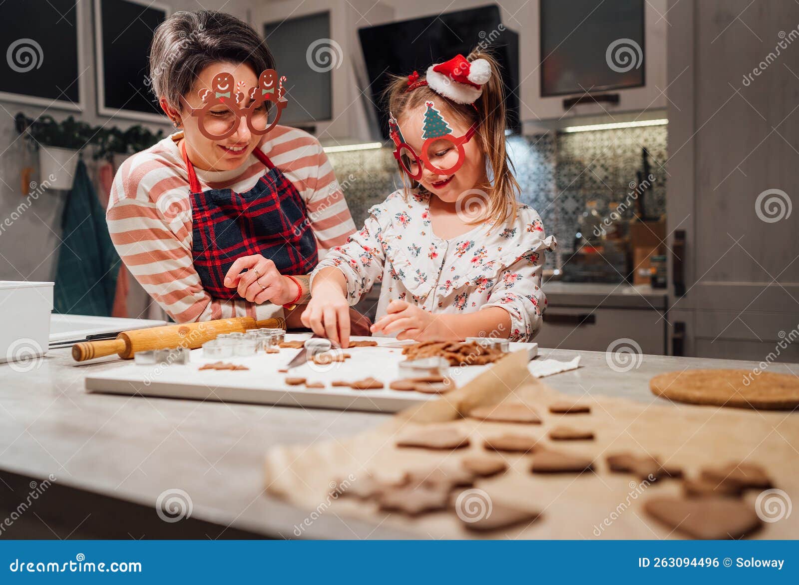 Cute Little Girl with Mother in Funny Glasses Making Homemade Dough Christmas Gingerbread Cookies Using Cookie Cutters Together in Stock Photo  image picture