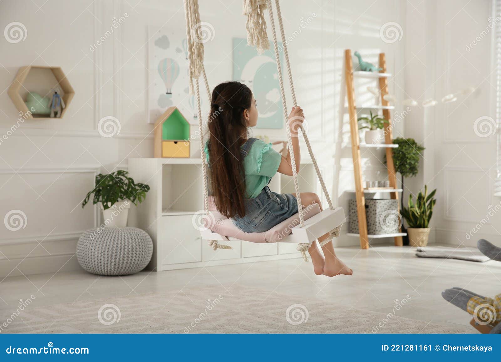 cute little girl playing on swing at home