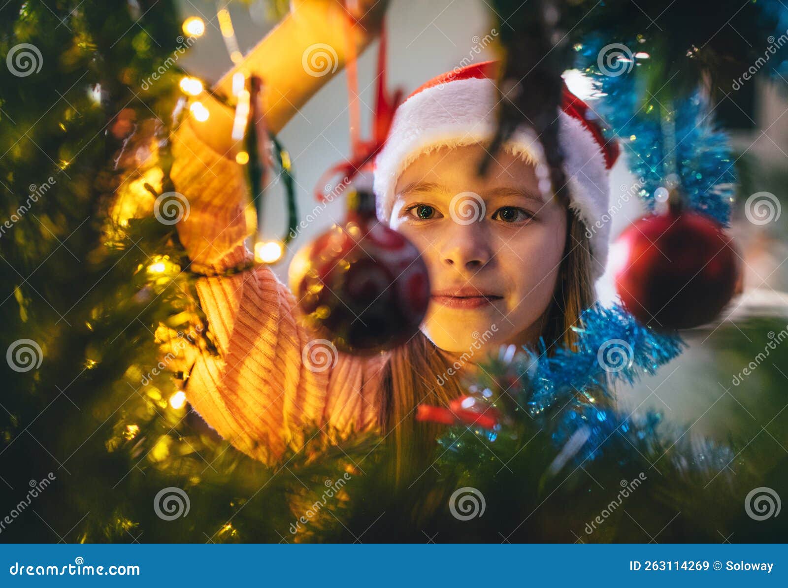 Cute Little Girl in Red Santa Hat Hanging a Magic Tree Decoration Ball ...