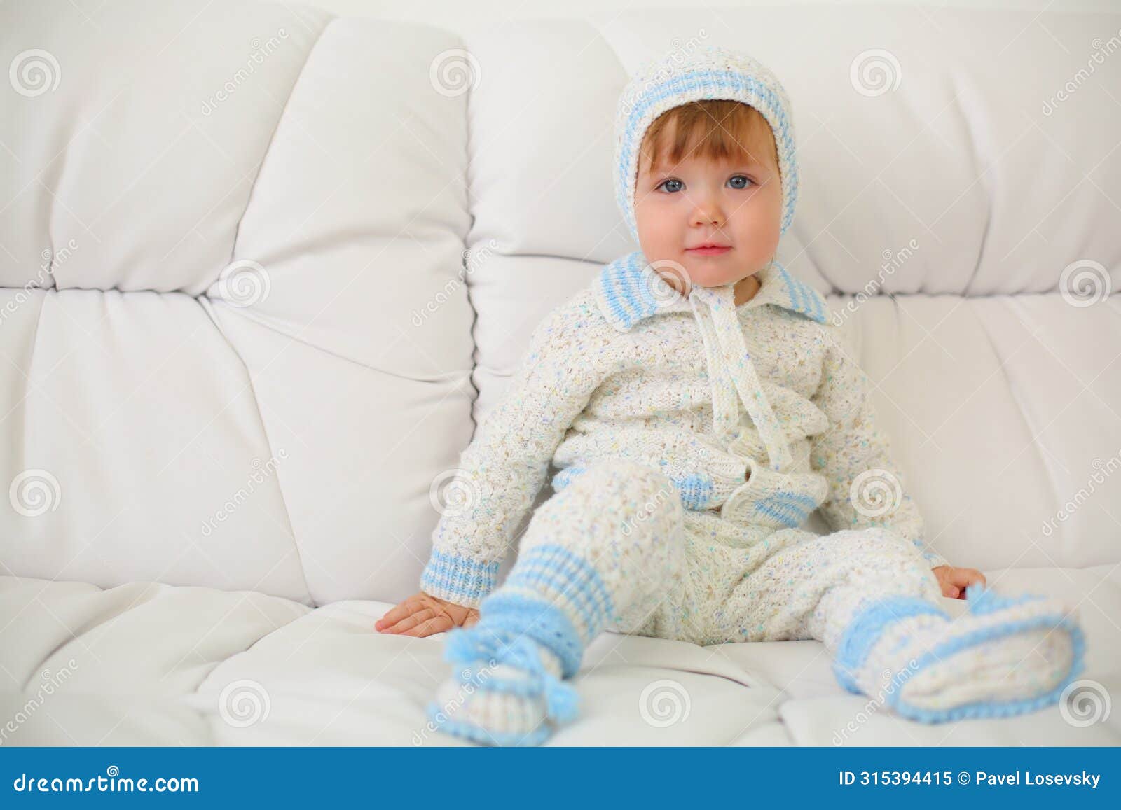 cute little kid in knitted suit and hat sits on