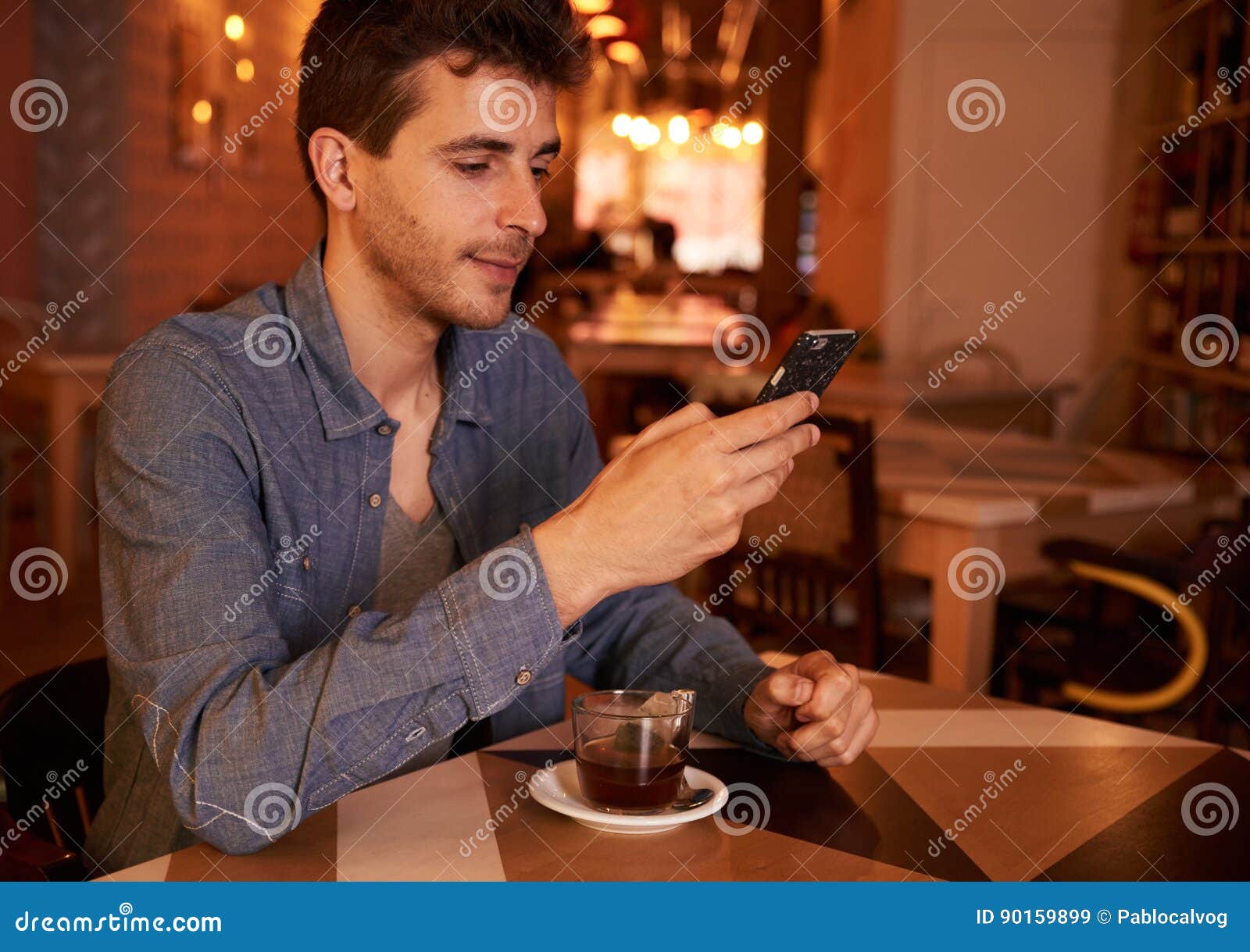 cute millenial male texting in restaurant