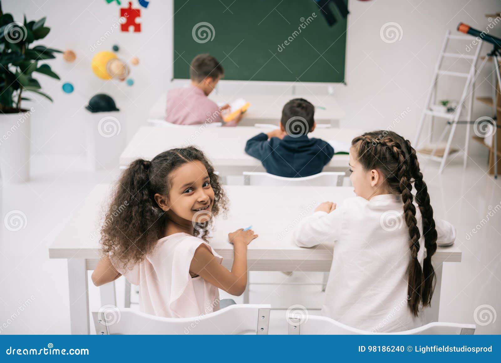 Cute Multiethnic Kids Sitting at School Desks and Studing in Classroom