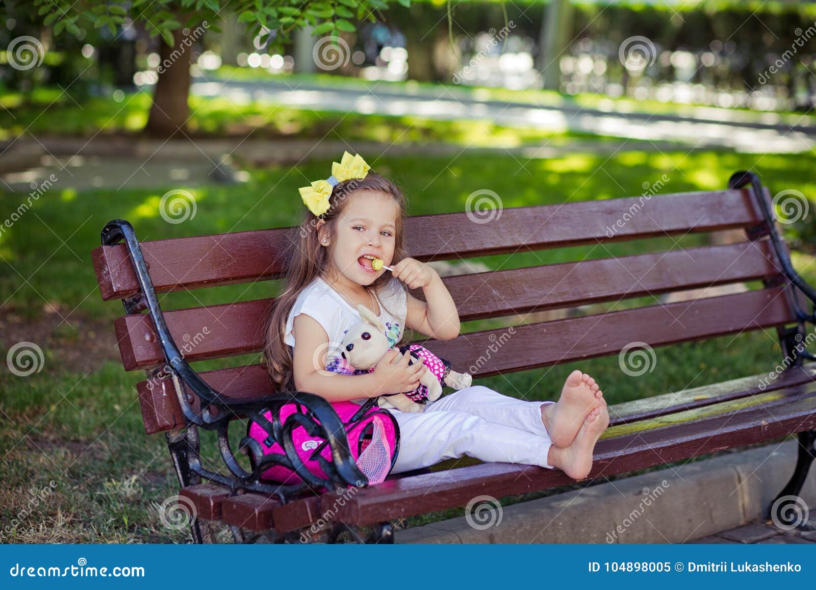 cute musical baby child girl with brunette hairs and stylish wear enjoying life sitting on wooden chair bench in summer awesome pa