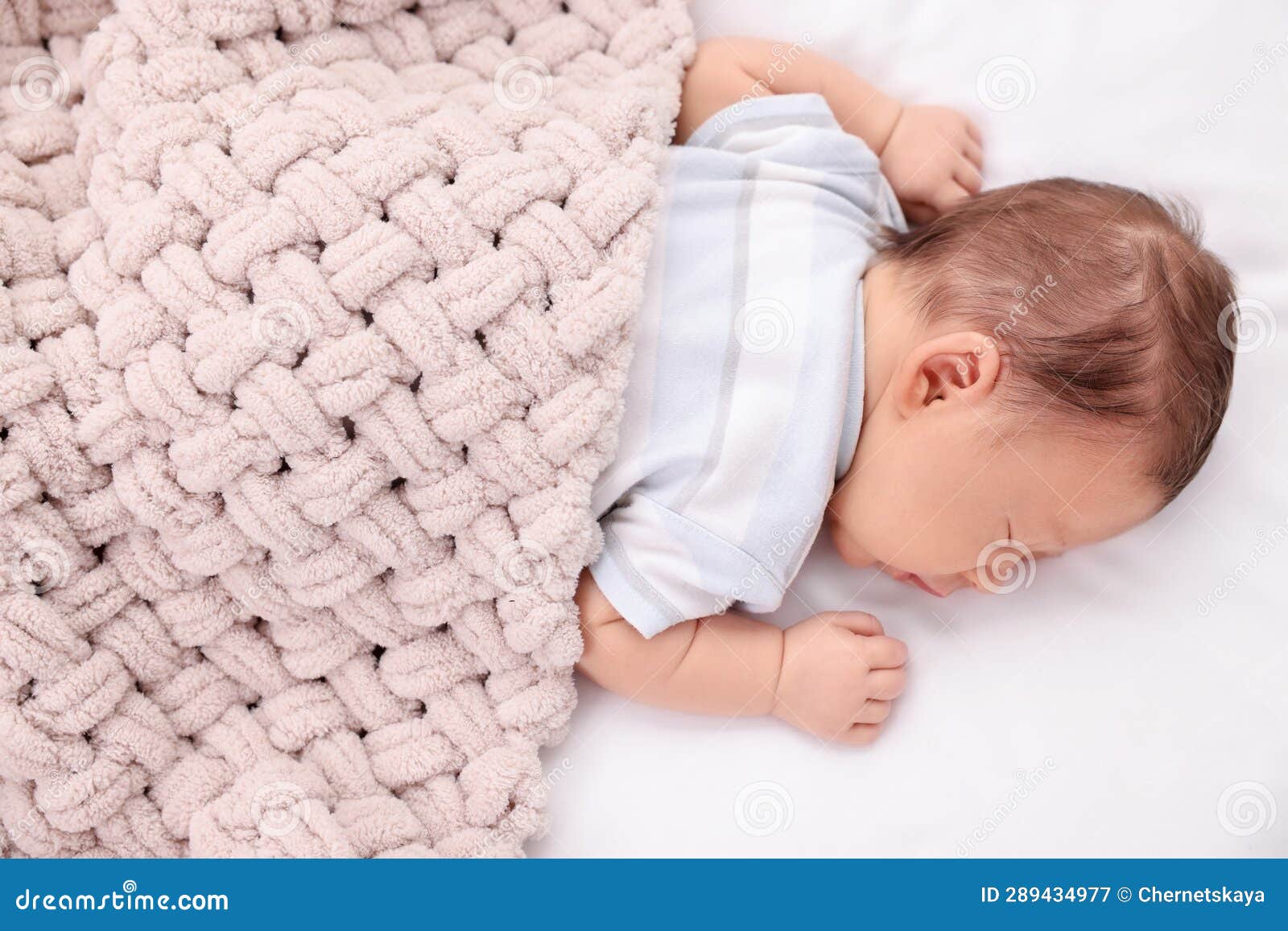 Cute Newborn Baby Sleeping Under Beige Soft Blanket on Bed Stock Image