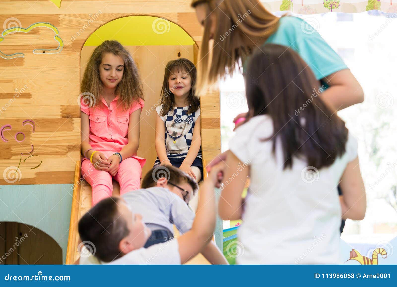 cute girls smiling during playtime supervised by a young teacher