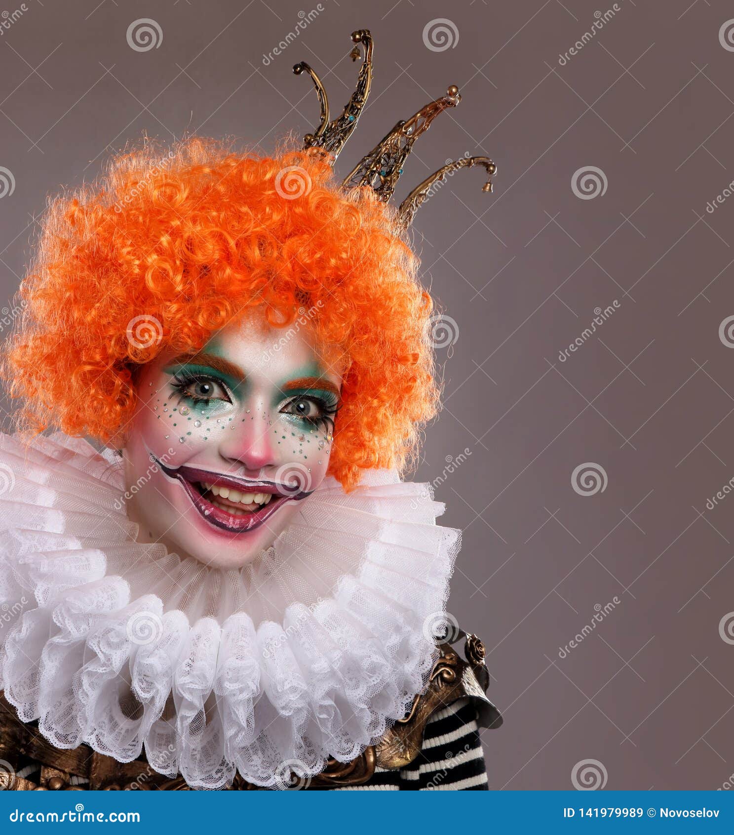 Cute red-haired clown.Girl in bright clown makeup. Close up. Stock Photo