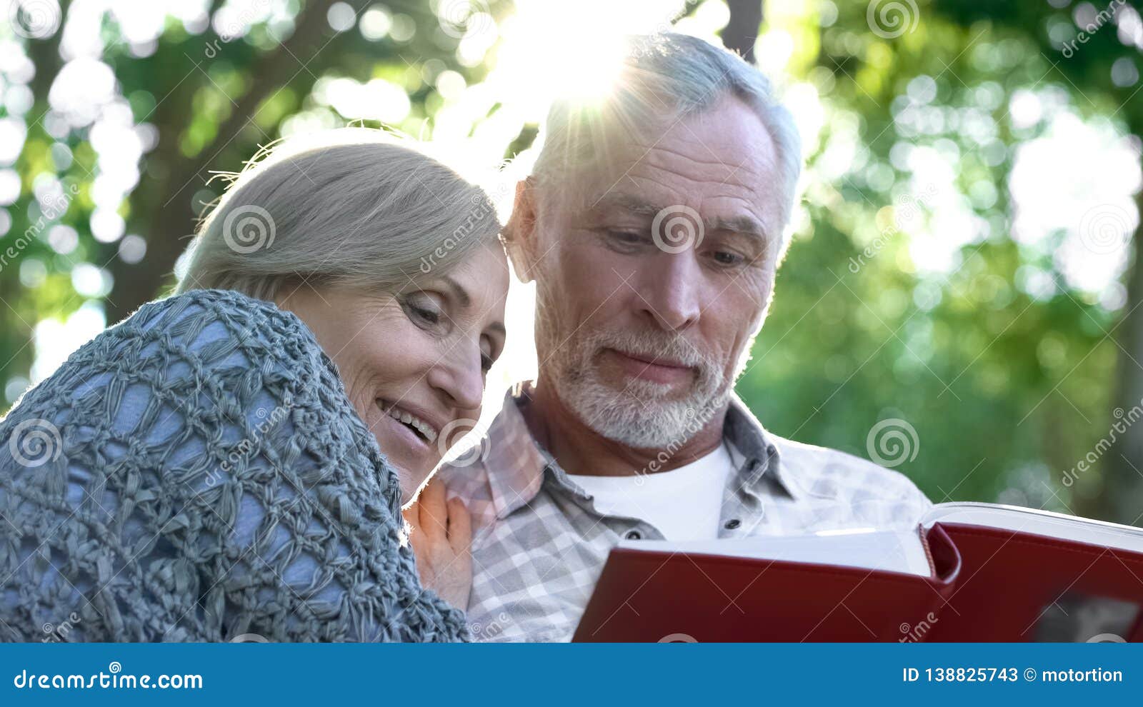 cute senior couple viewing photoalbum, remembering funny moments of life