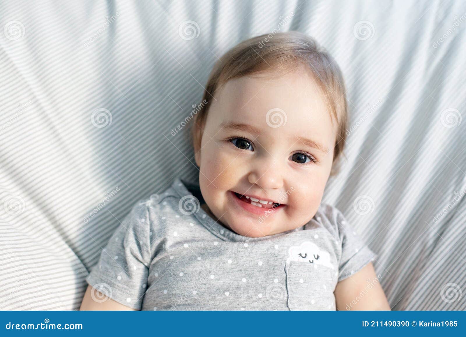 Cute Smiling Baby Girl Laying in the Bed in Morning Sun Light Stock