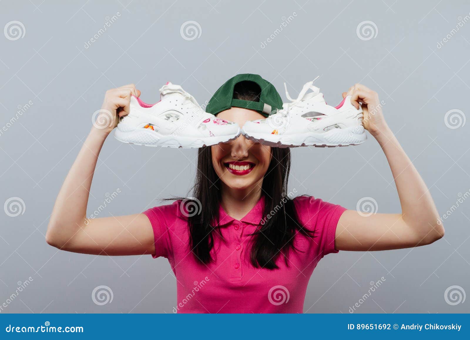 A Cute Teenage Girl in Her Skirt Holding Up Her Shoes with a Confused ...