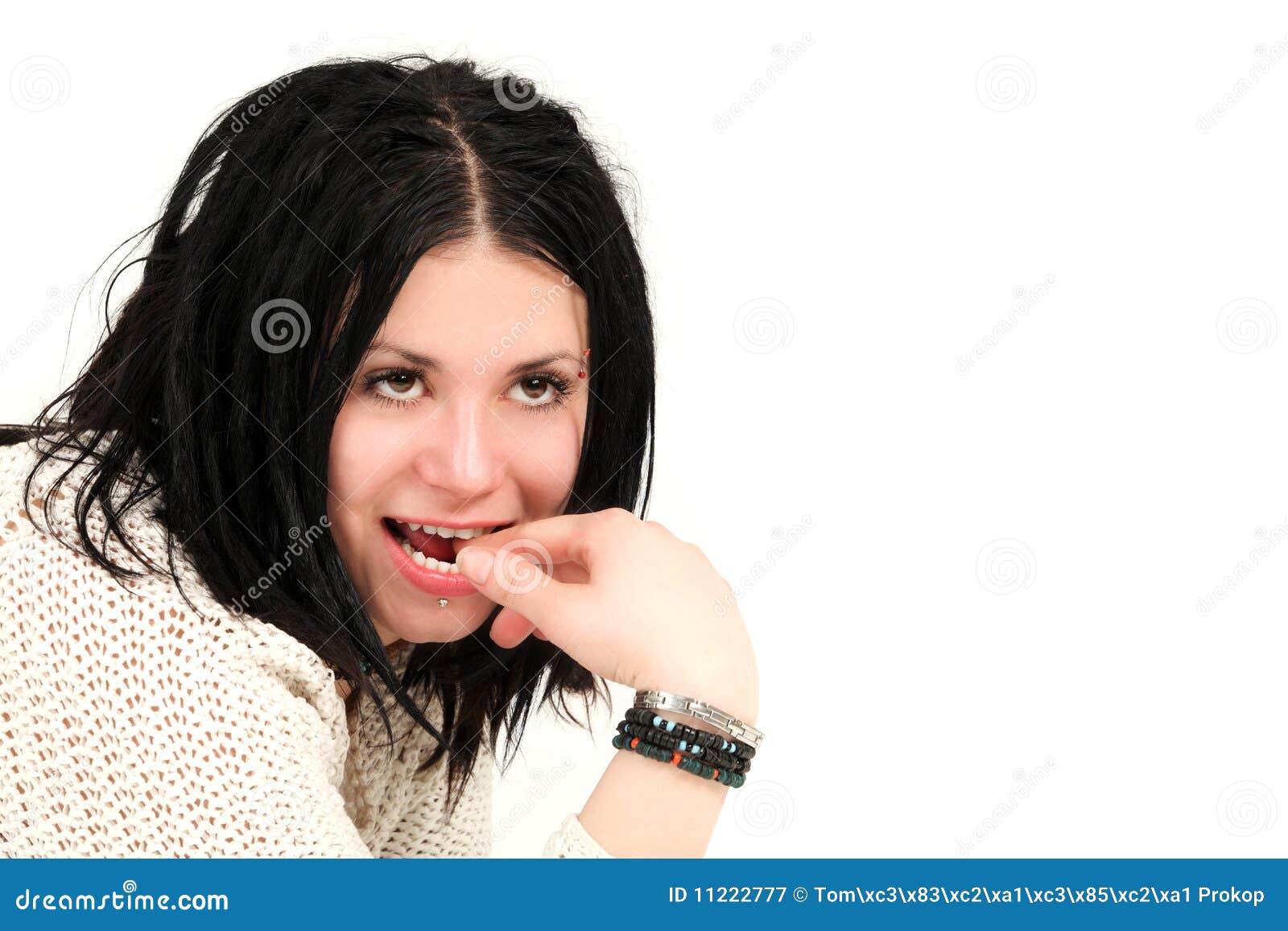 Cute teenager with face piercings. Portrait of young teenage girl with finger in mouth, studio shot