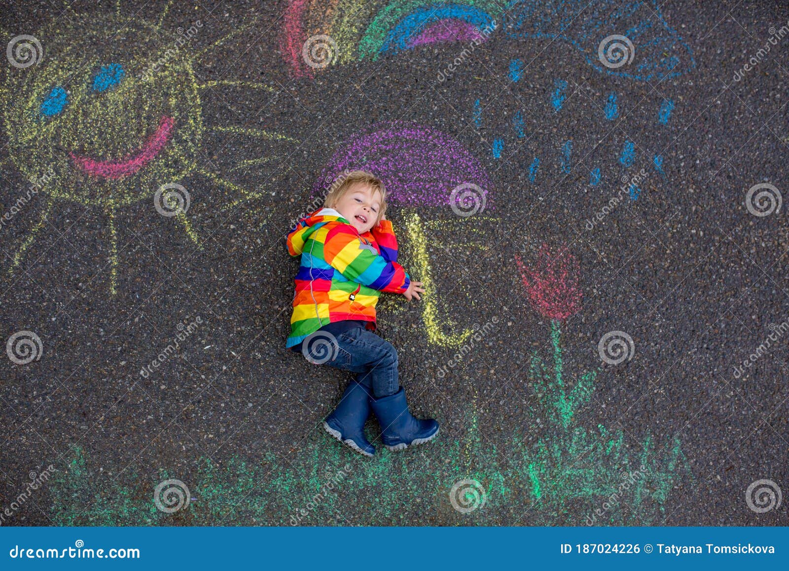 Cute Toddler. Playing in the Rain with Chalks, Drawing on the Asphalt