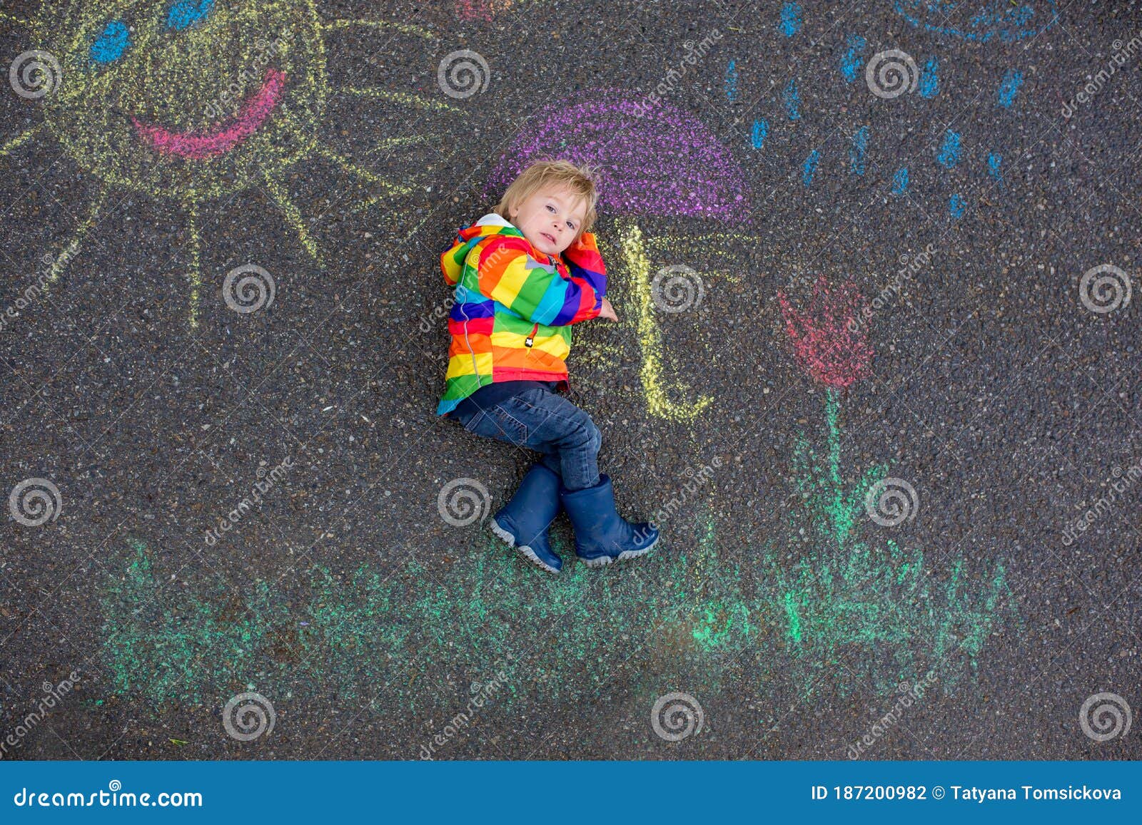 Cute Toddler. Playing in the Rain with Chalks, Drawing on the Asphalt