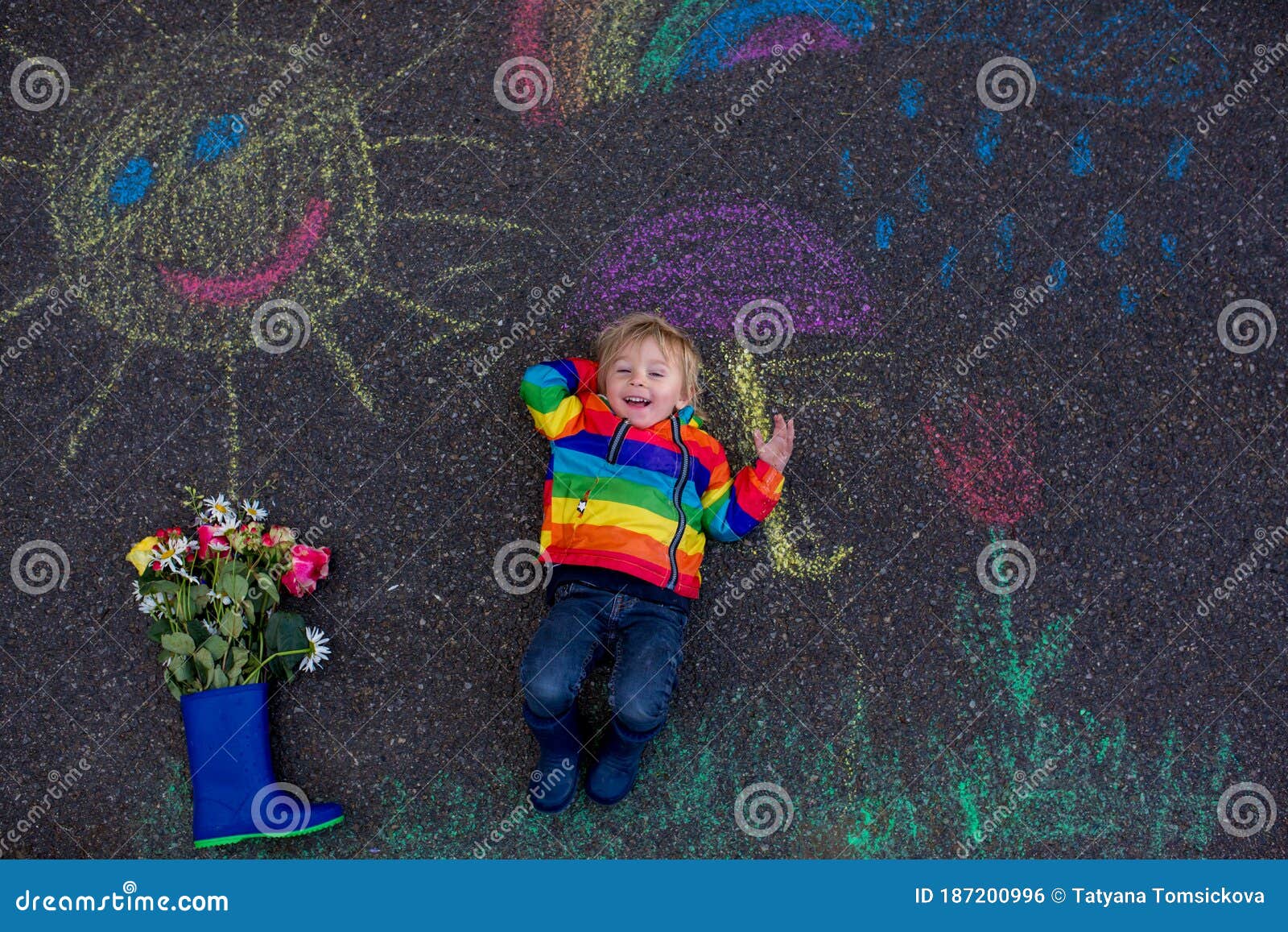 Cute Toddler. Playing in the Rain with Chalks, Drawing on the Asphalt