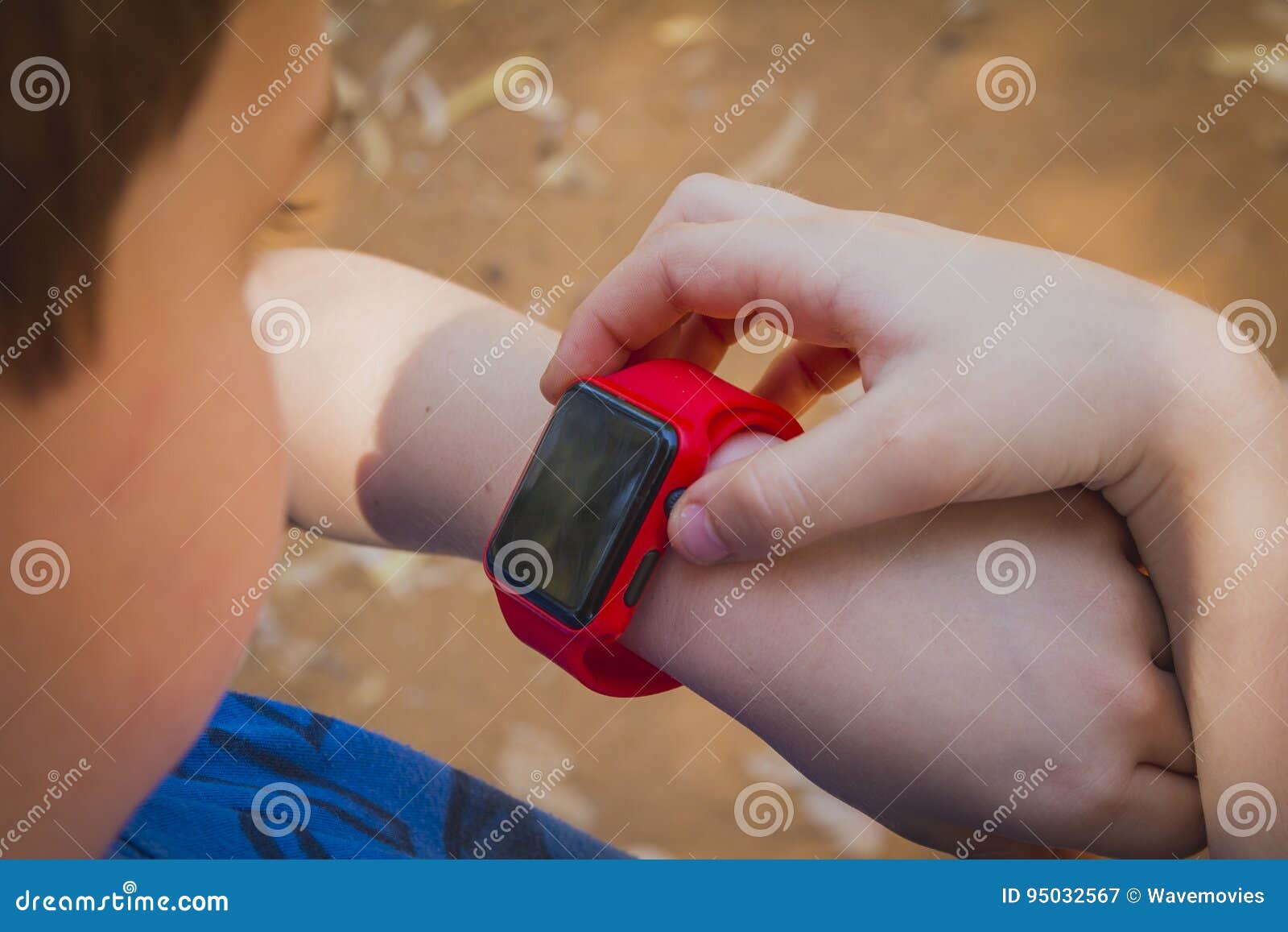 Cute Young Boy Looking at His Red Smart Watch and Touching it Stock Image - Image of caucasian
