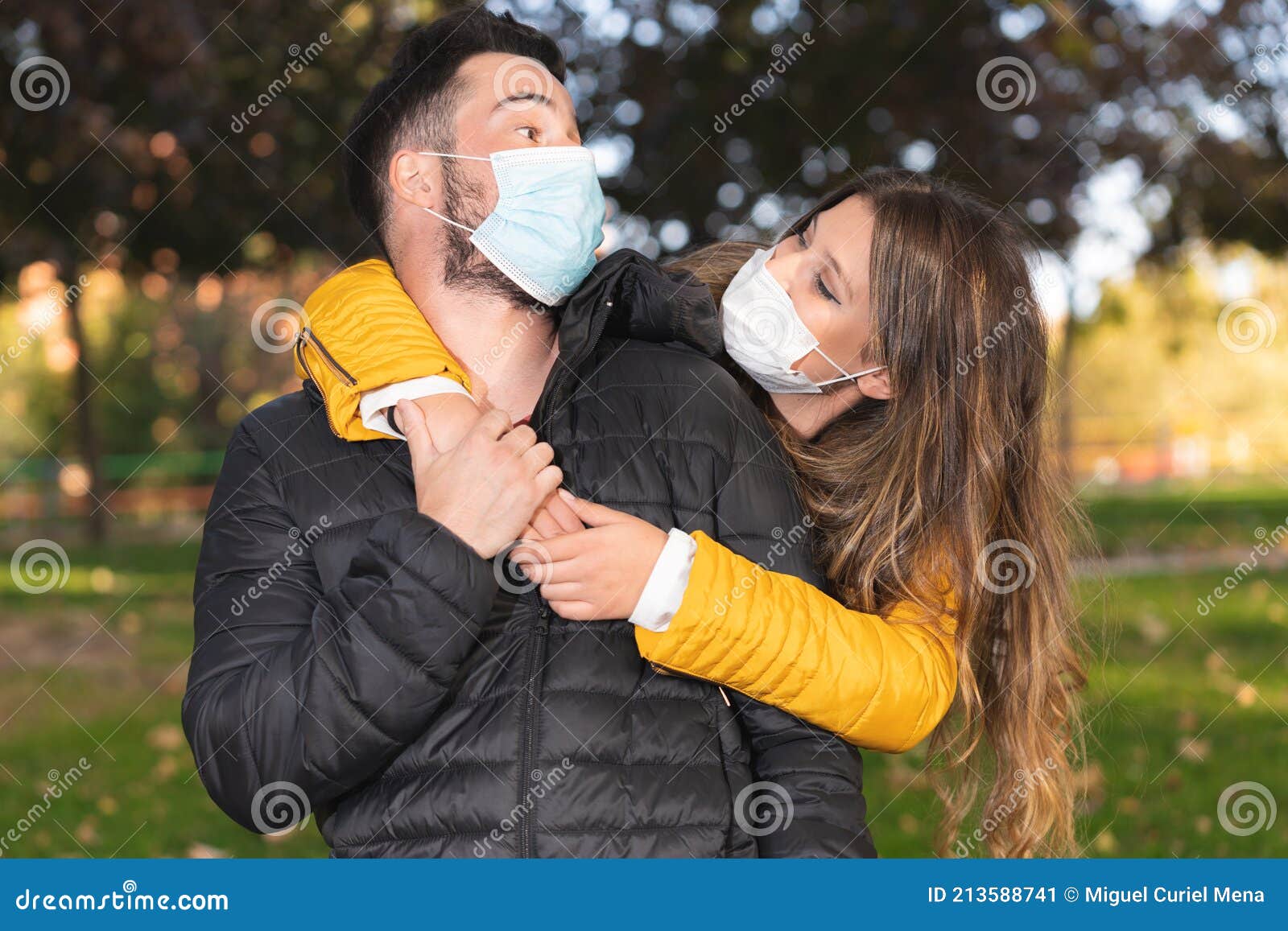 Cute Young Couple with Face Masks Looking at Each Other in a Park Stock ...