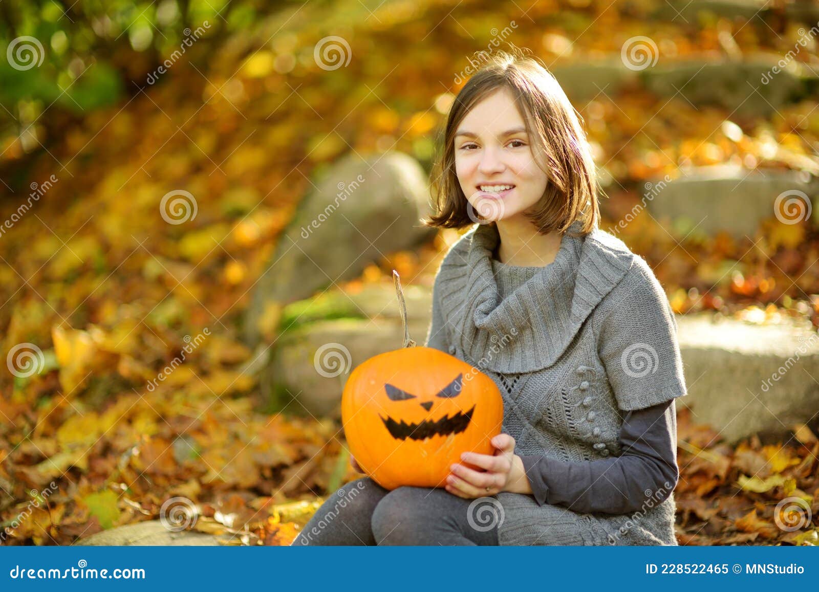 Cute Young Girl Holding a Small Pumpkin with Painted Scary Face on ...