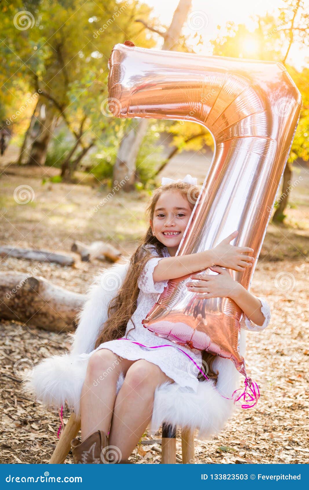 cute young girl playing with number seven mylar balloon outdoors