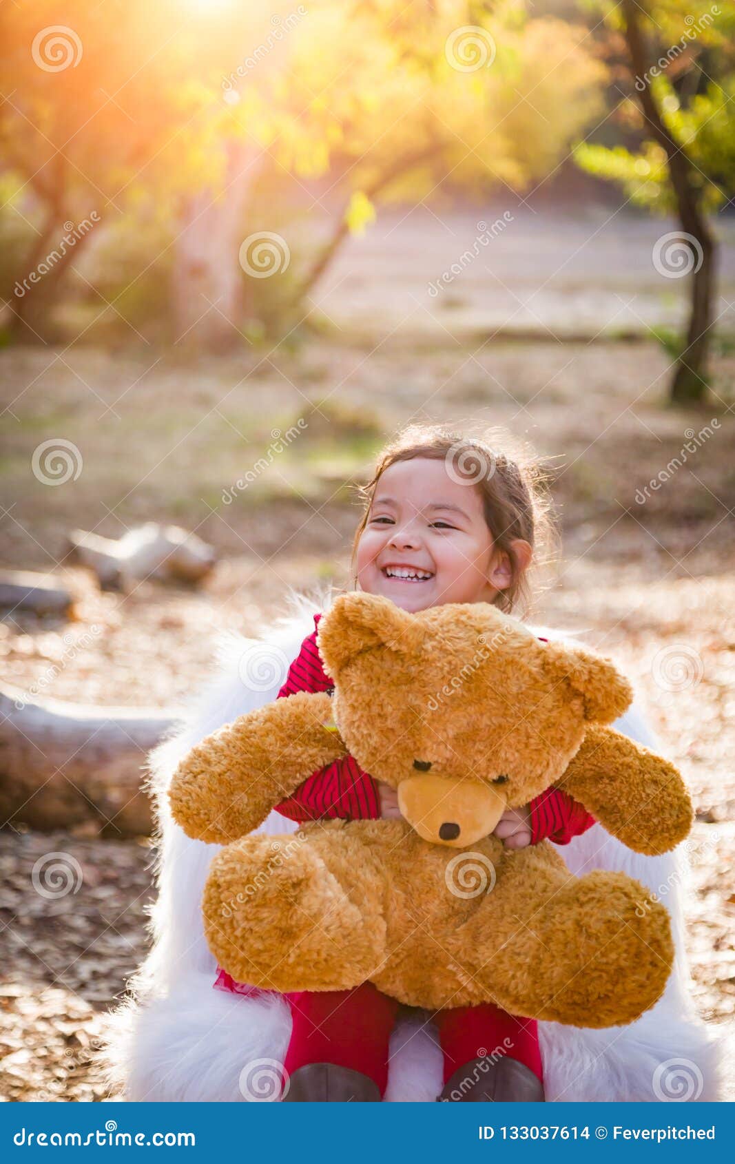 Cute Young Mixed Race Baby Girl Hugging Teddy Bear Outdoors Stock