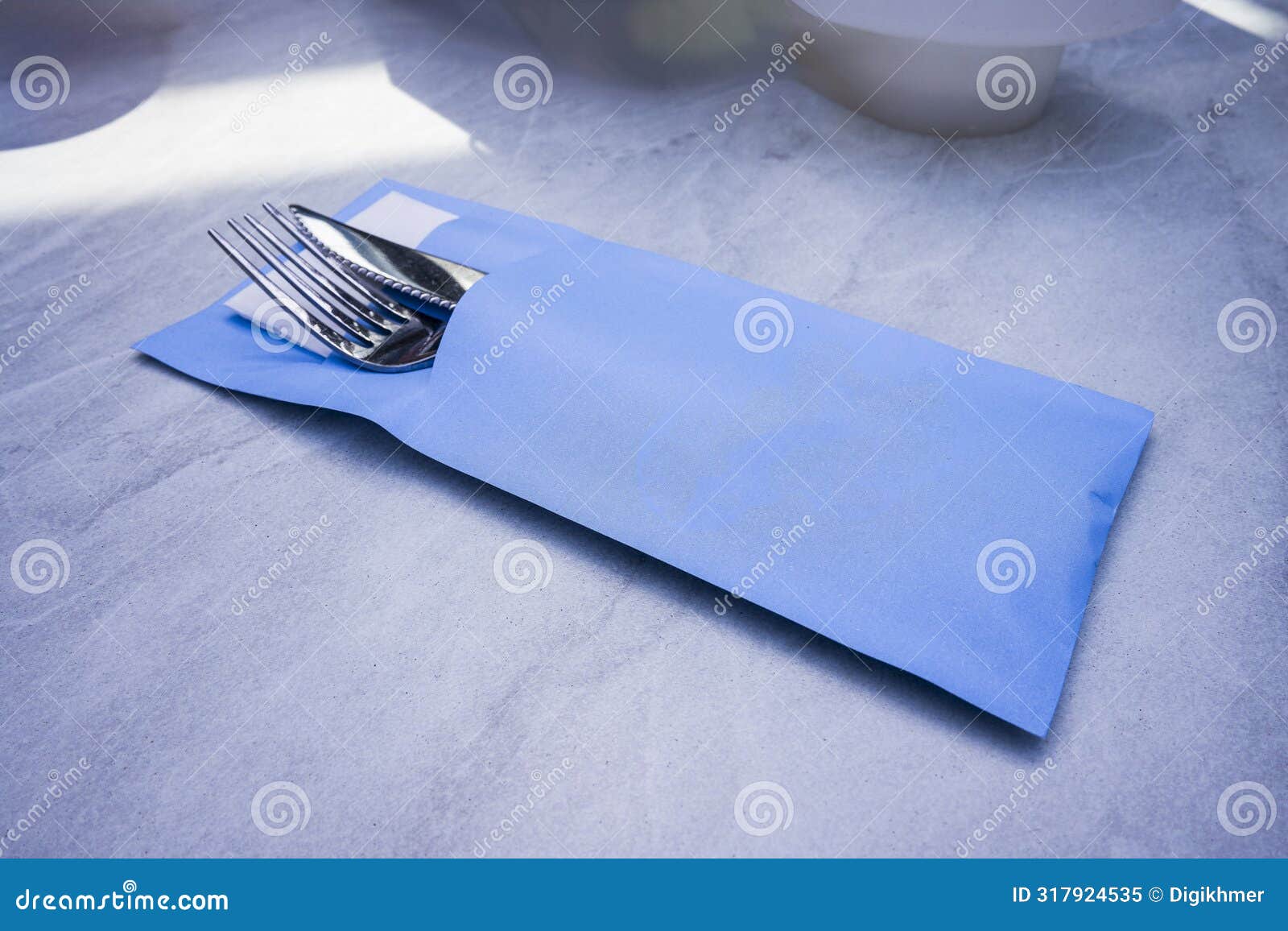cutlery set with fork, knife, and tissue wrapped inside a blue paper envelope