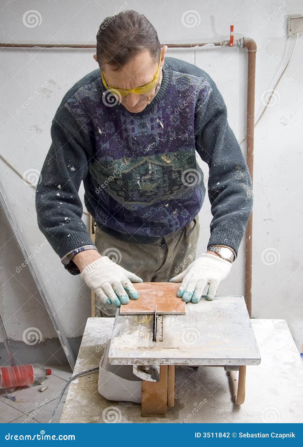 Cutting tiles. A man at a cutting machine, working on floor tiles, protective glasses.