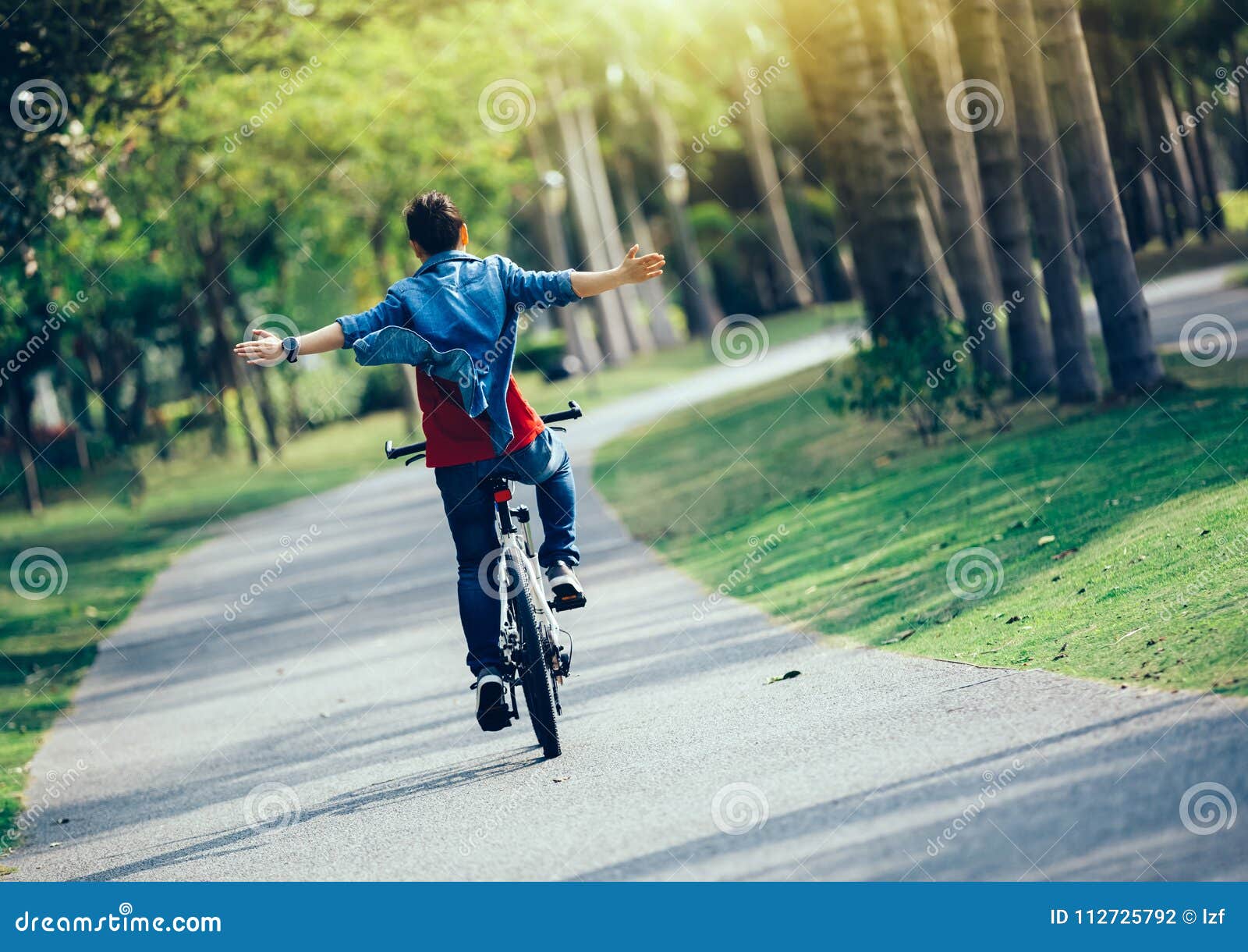 Happy woman cyclist riding bike in spring tropical park