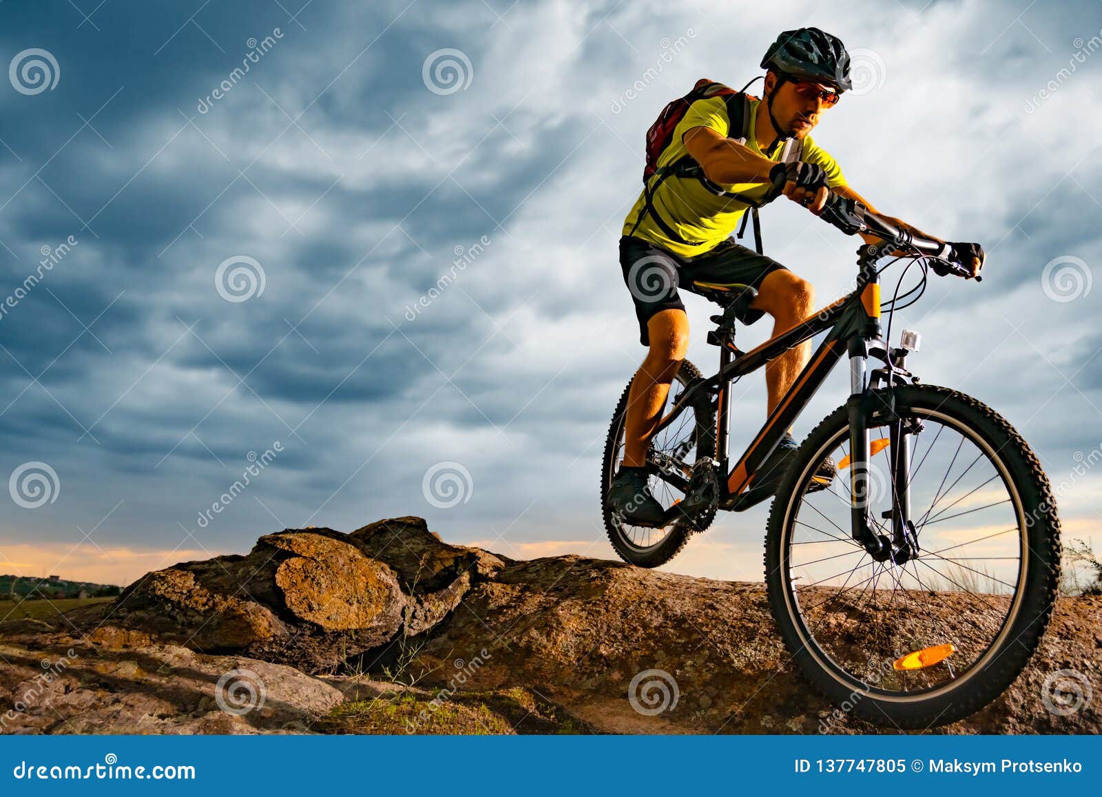 cyclist riding the mountain bike on rocky trail at sunset. extreme sport and enduro biking concept.