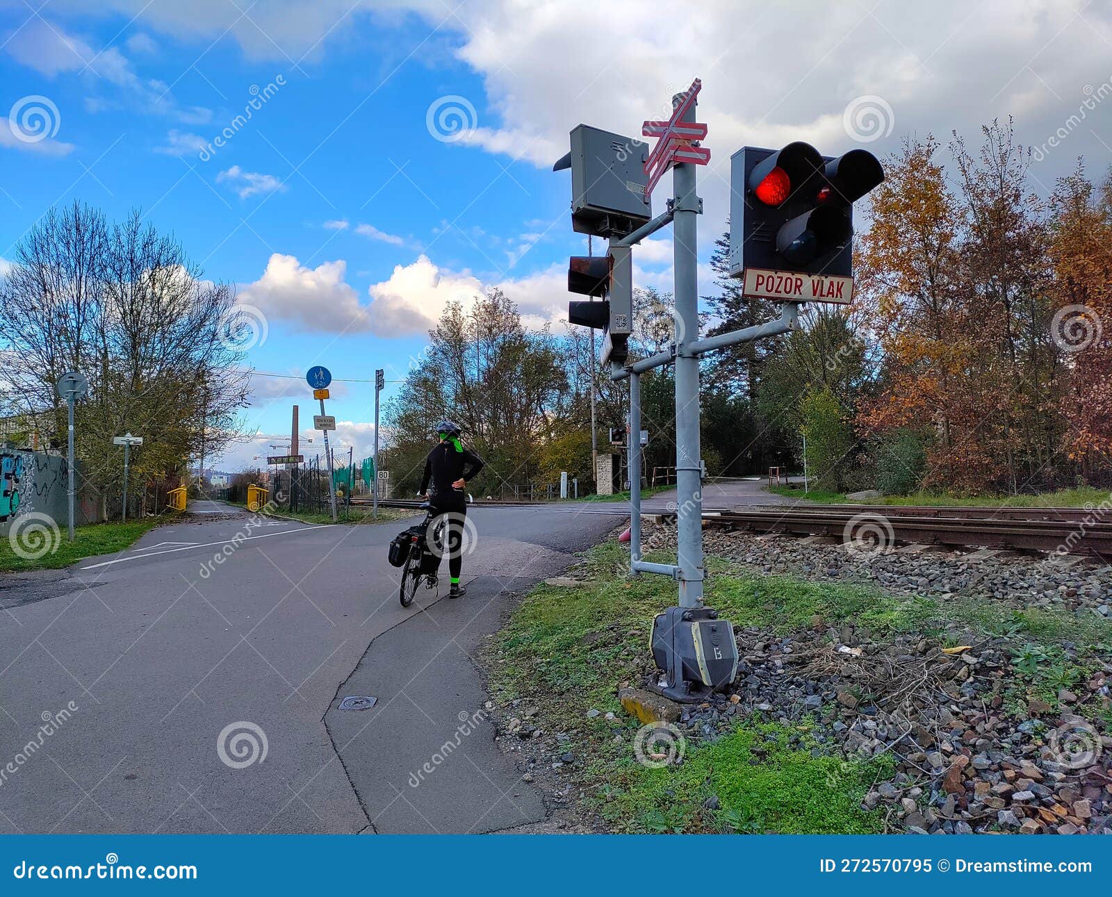 a cyclist is waiting at railway crossing with stoplights being turned on
