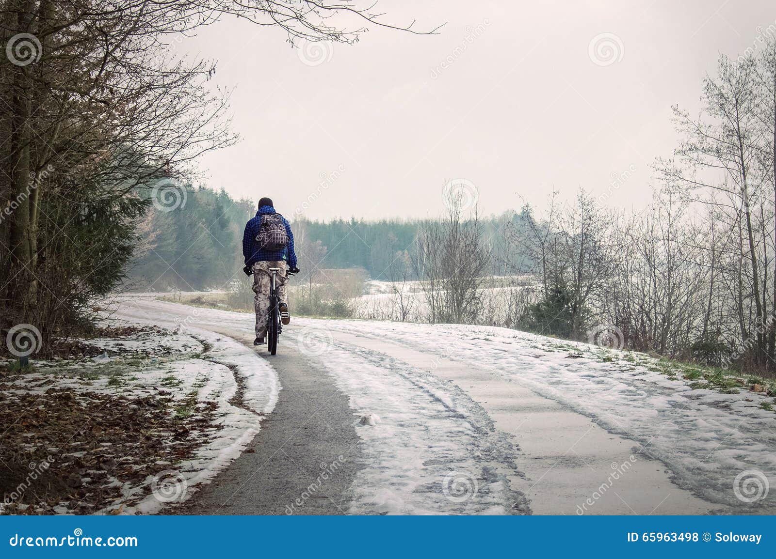 Cycliste d'hiver sur la route neigeuse