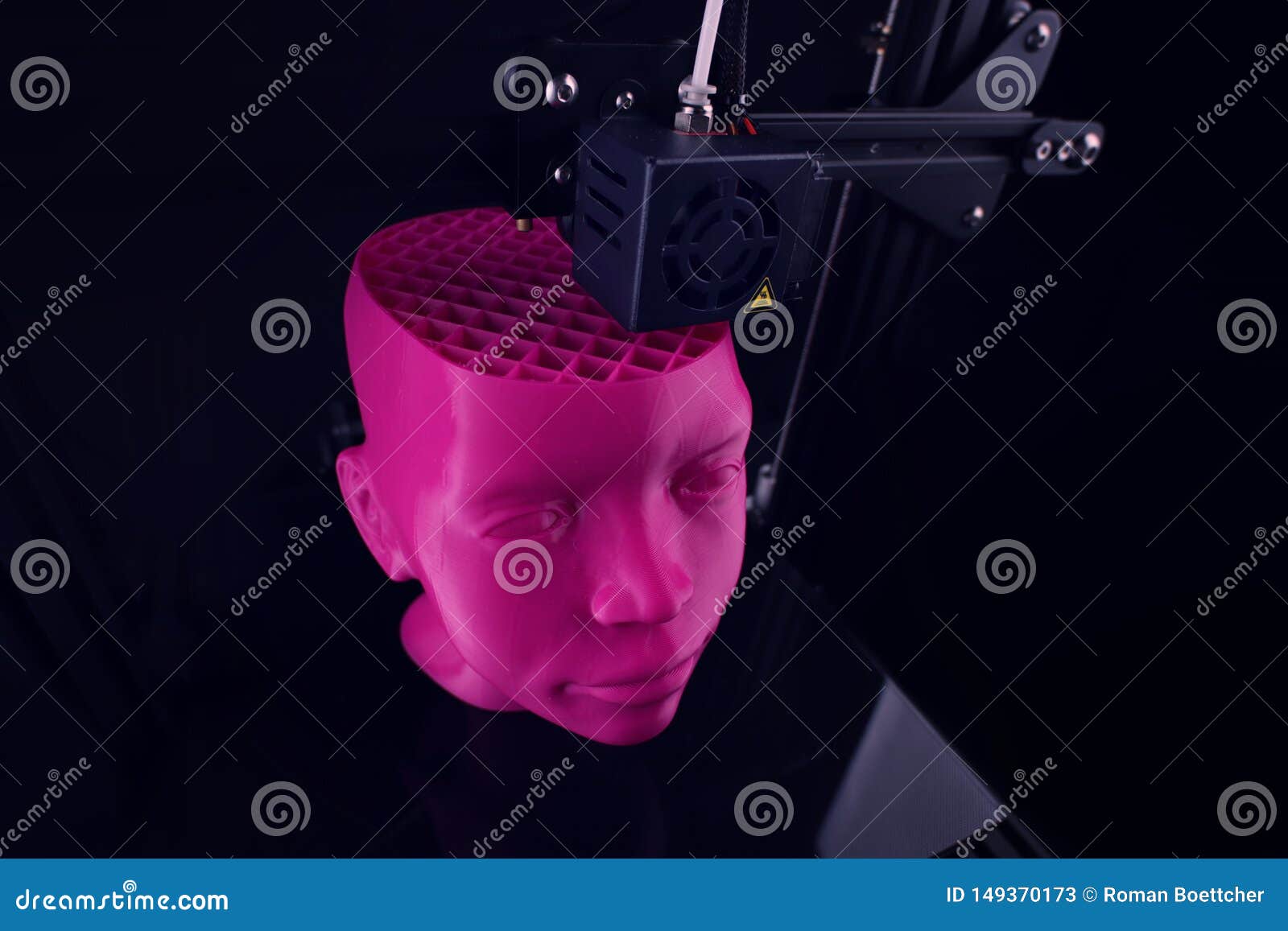 a 3d printer produces a futuristic sculptural humanoid head from pink plastic in foggy light.