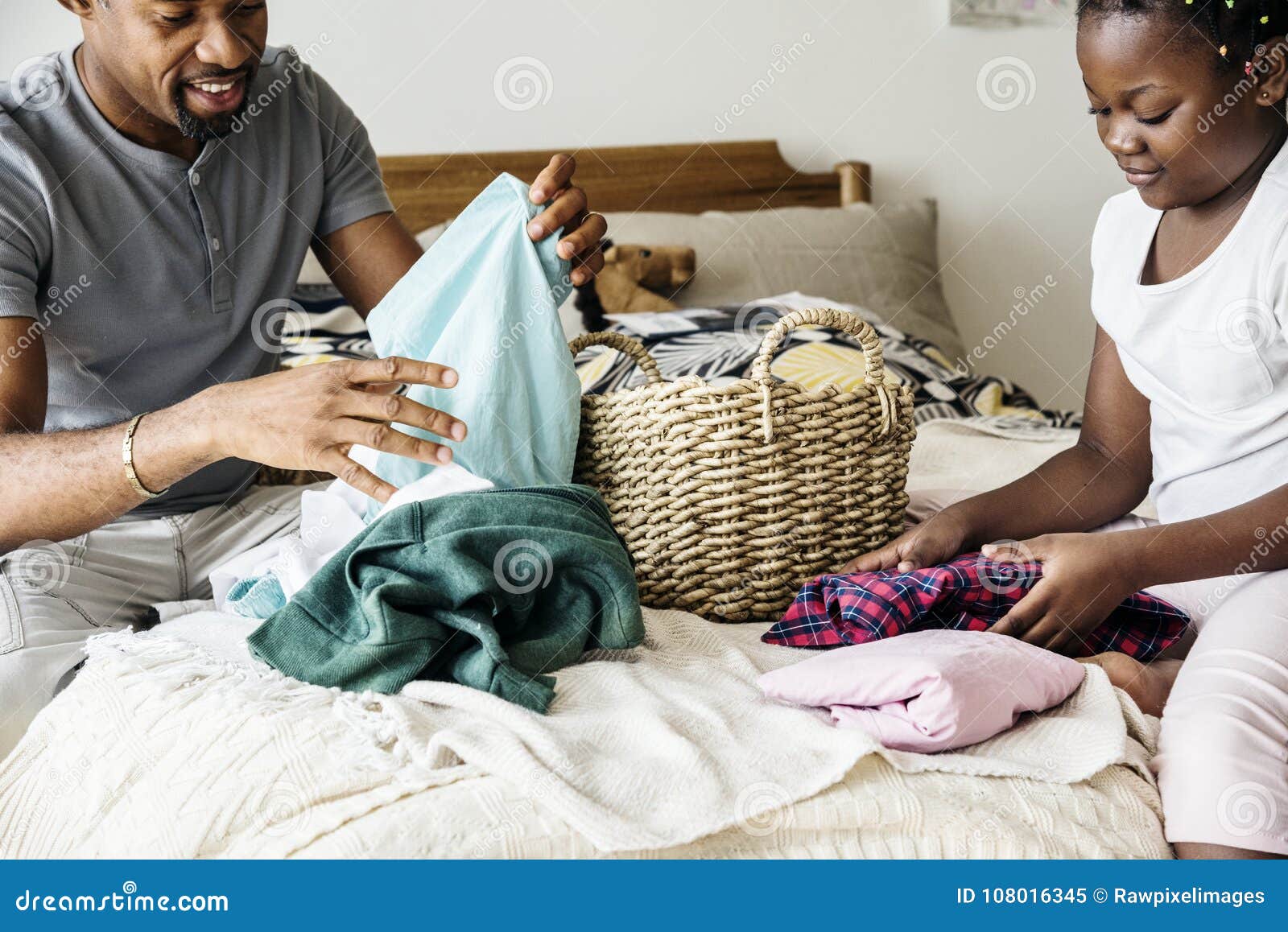 dad and daughter folding clothes in bedroom together