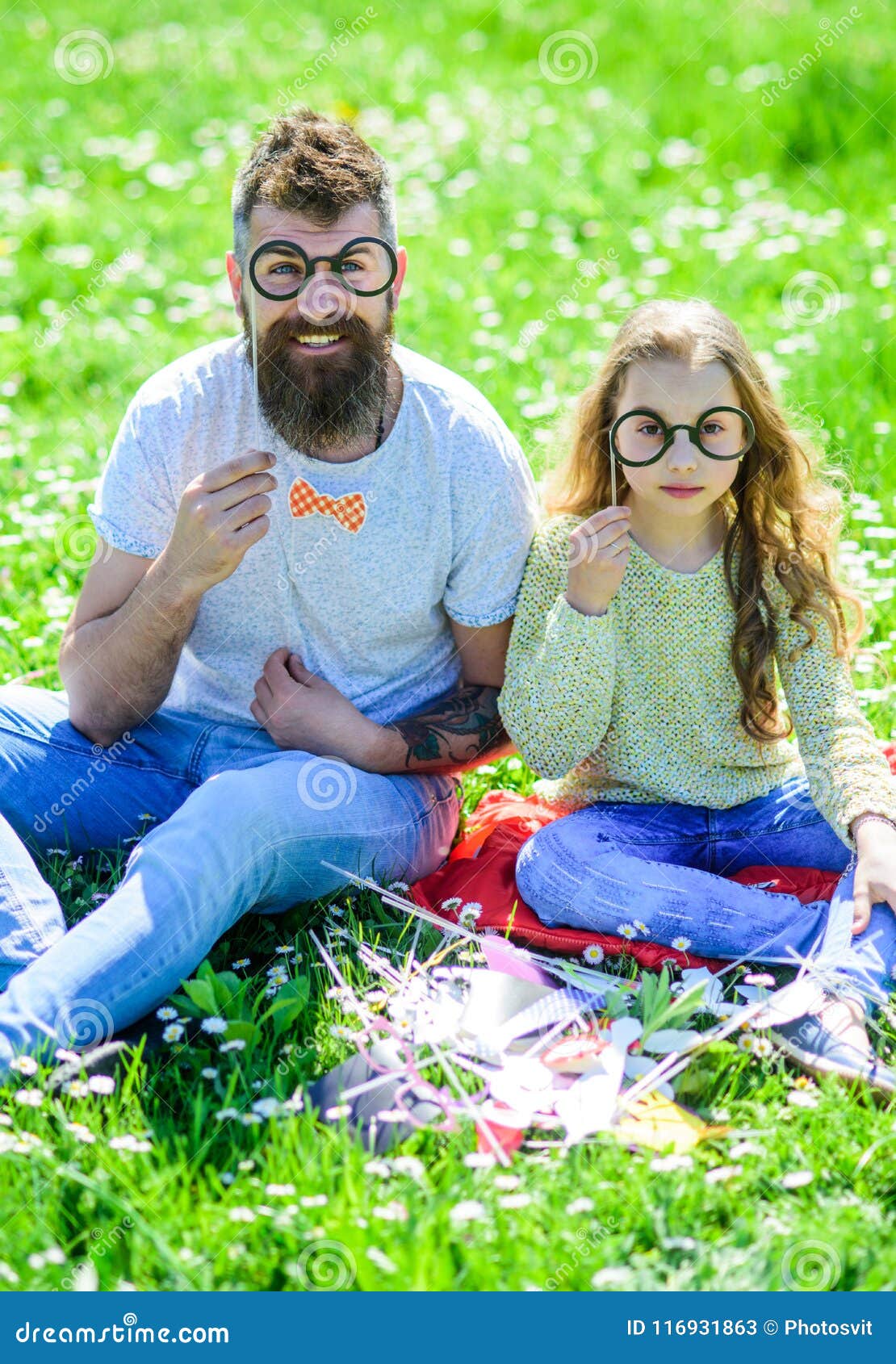 dad and daughter sits on grass at grassplot, green background. child and father posing with eyeglases photo booth