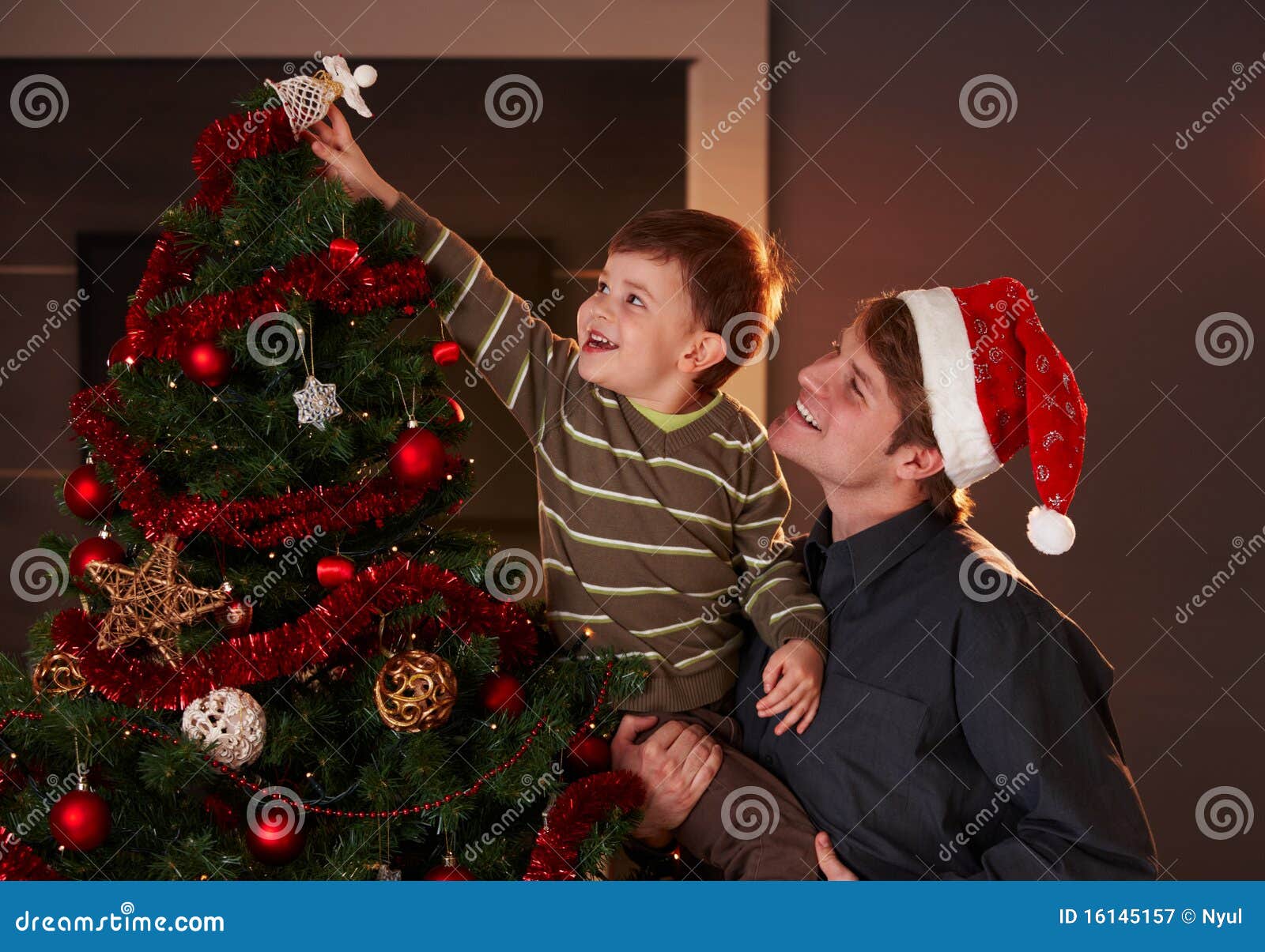dad helping boy to decorate christmas tree