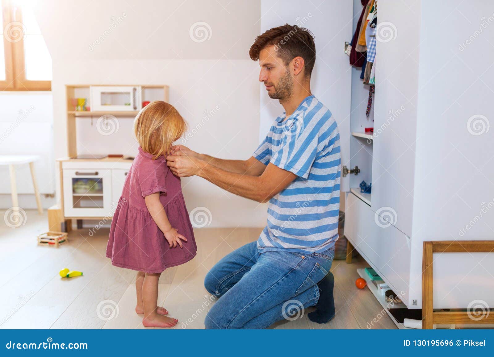 dad is helping toddler daughter to get dressed