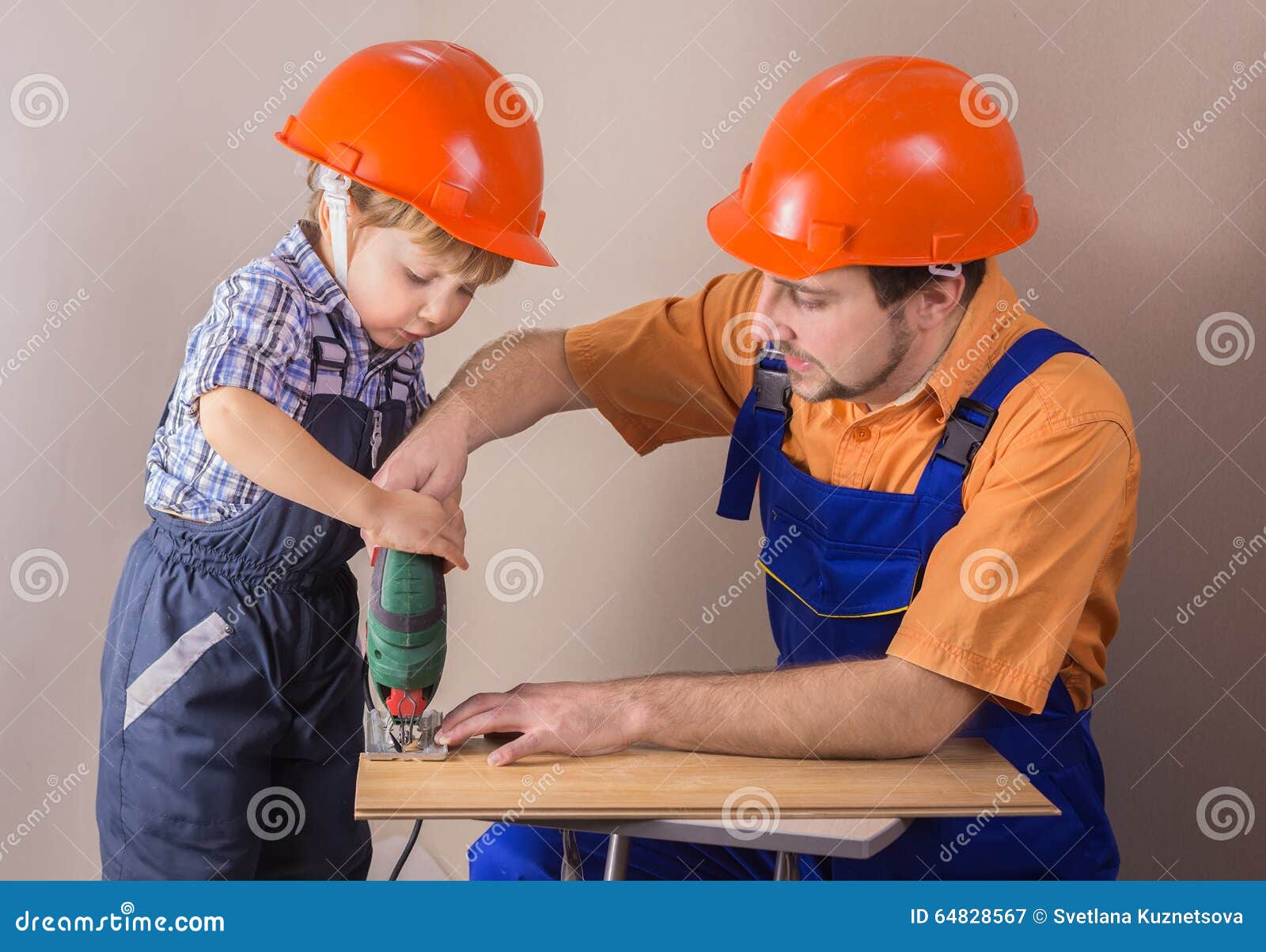 dad with young son in protective helmet working jigsaw