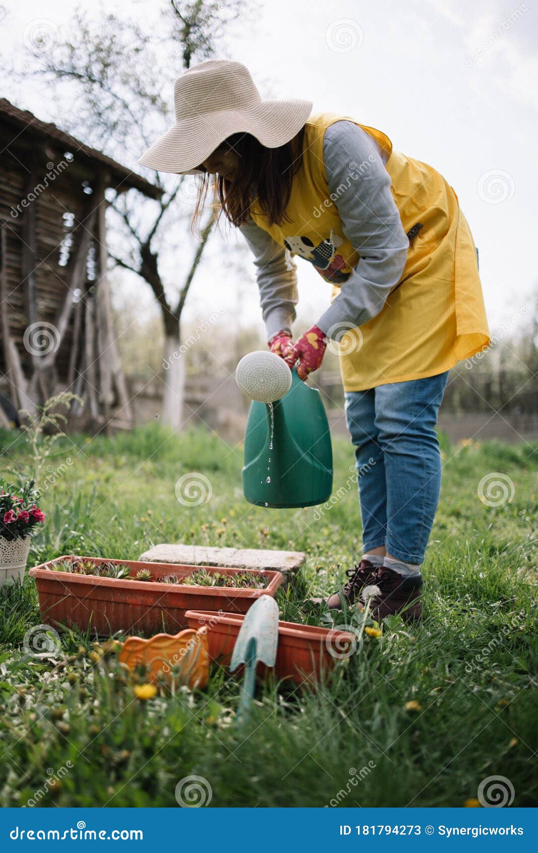 Mujer en guantes de jardinería con pala sosteniendo planta de