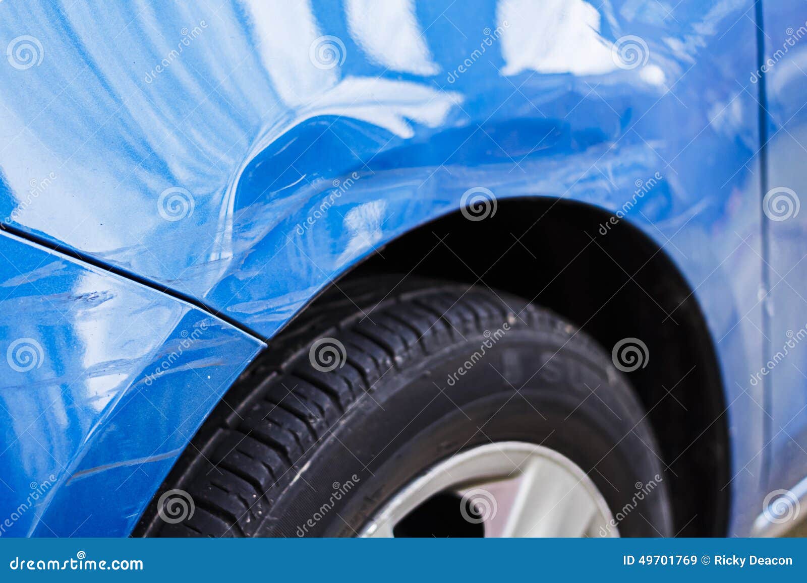 Closeup of side part of auto wheel and fender with cracks, dents