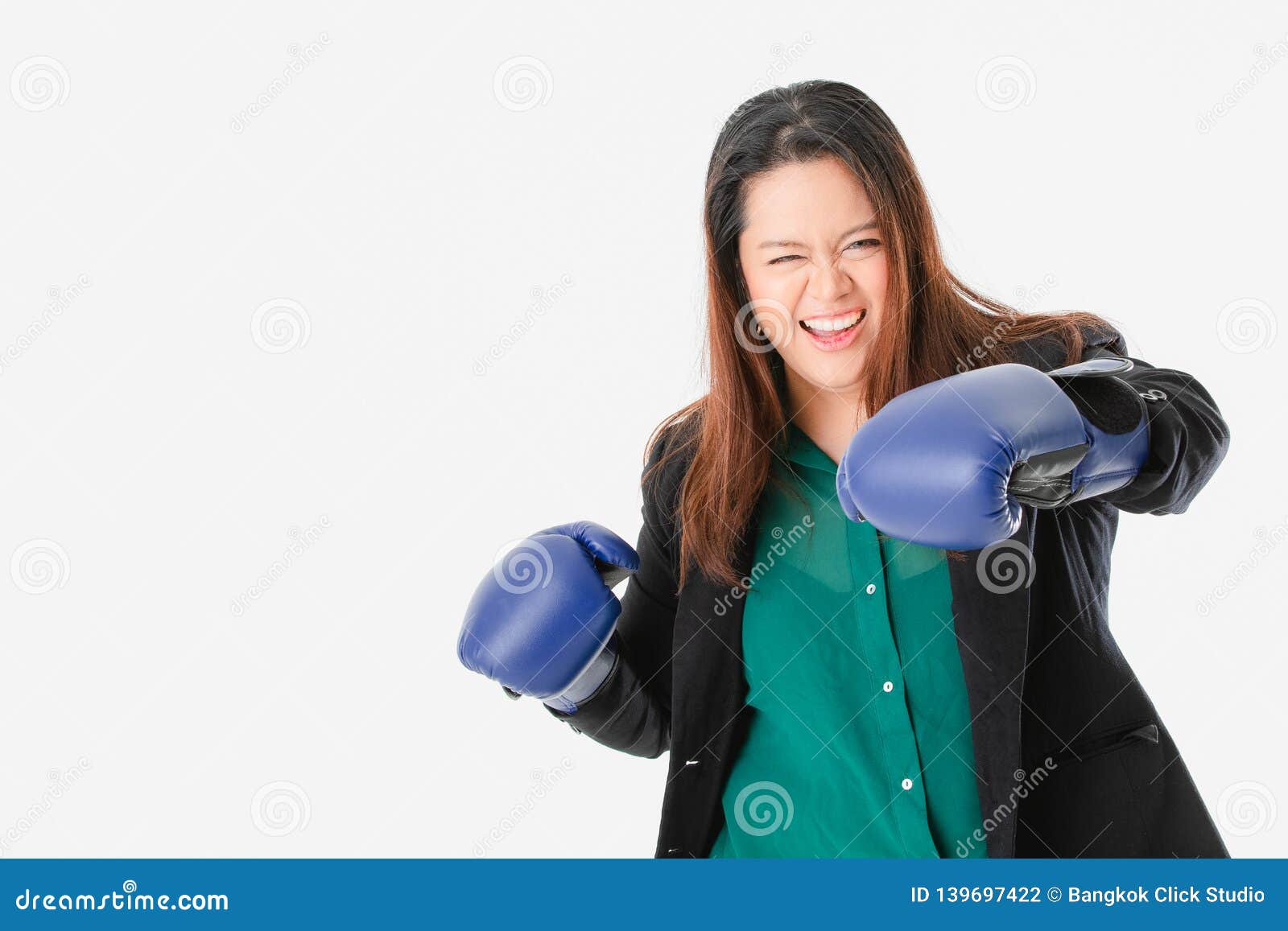 Dame dodue dans occasionnel futé. Portrait haut étroit de jeune, dodue, belle, asiatique dame, dans la chemise occasionnelle et verte intelligente, gants de boxe bleus de port, posant par espièglerie pour l'action de combat, regard à la caméra, sur le fond blanc d'isolement