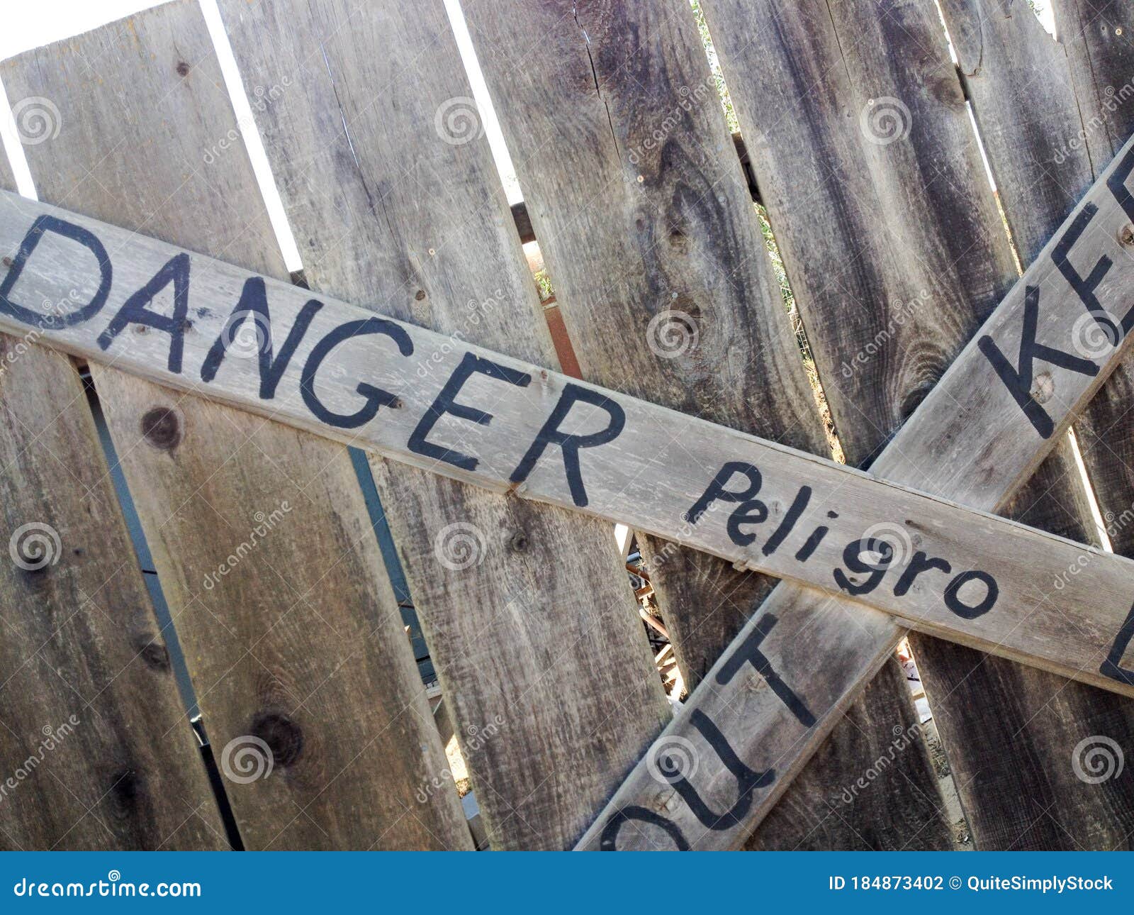 danger keep out peligro sign painted on wood fence