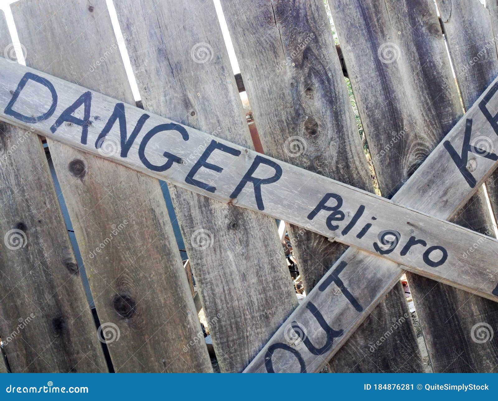 danger keep out peligro sign painted on wood fence