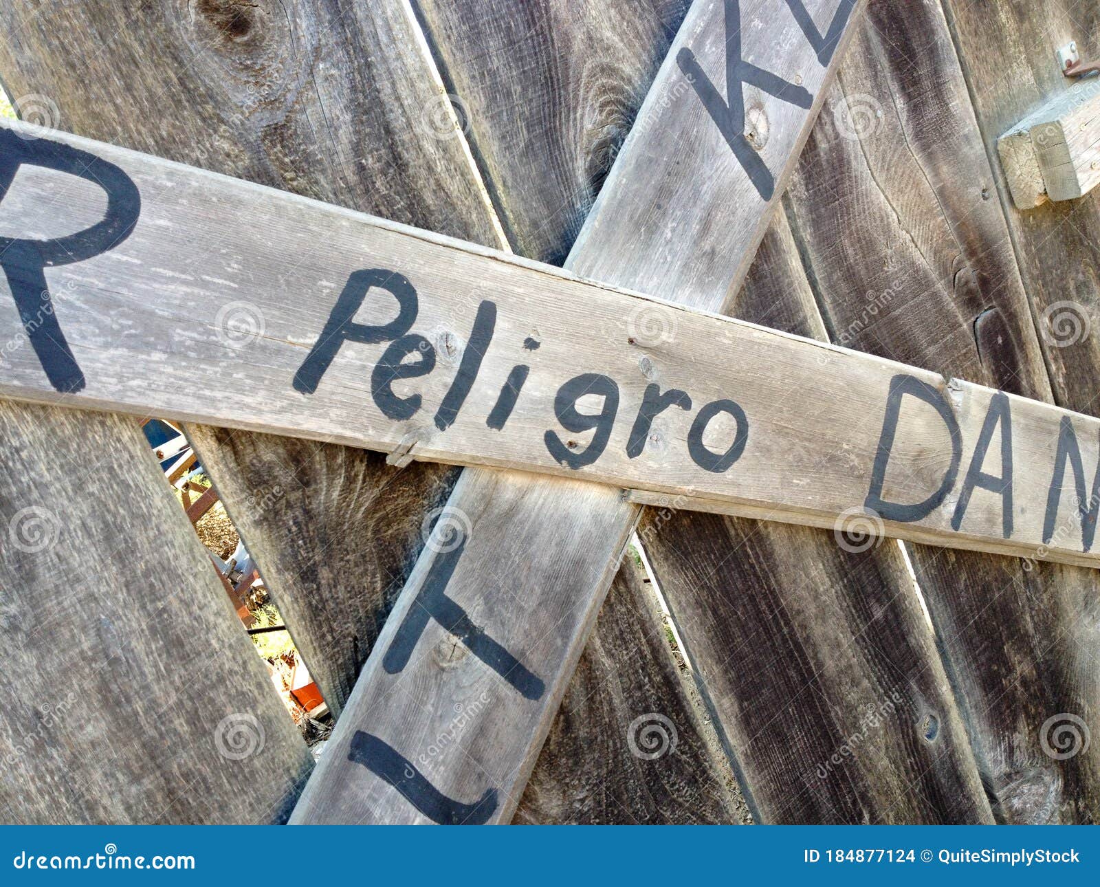 danger keep out peligro sign painted on wood fence