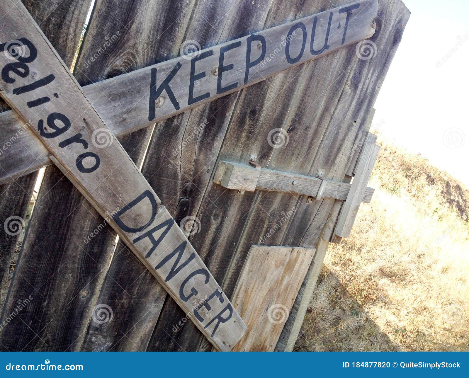 danger keep out peligro sign painted on wood fence