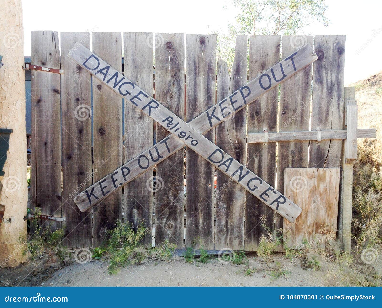 danger keep out peligro sign painted on wood fence