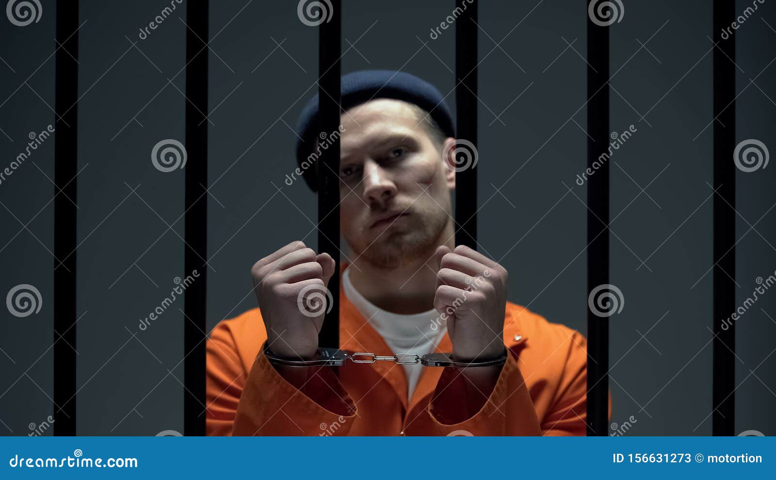 Handcuffed Hands Of A Prisoner Behind The Bars Of A Prison Royalty Free