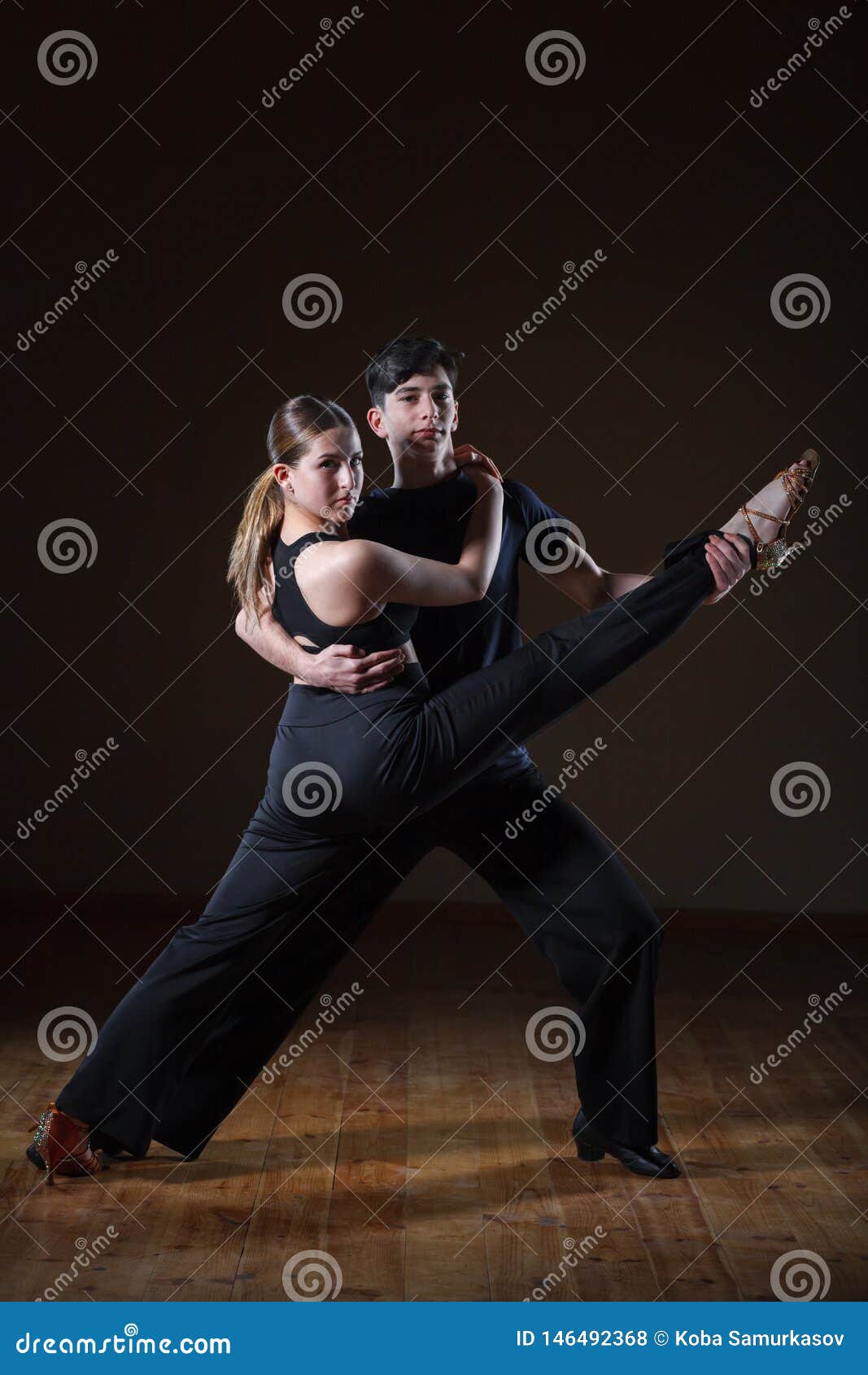 Dançarinos novos bonitos no salão de baile isolado no fundo preto, dança dos pares