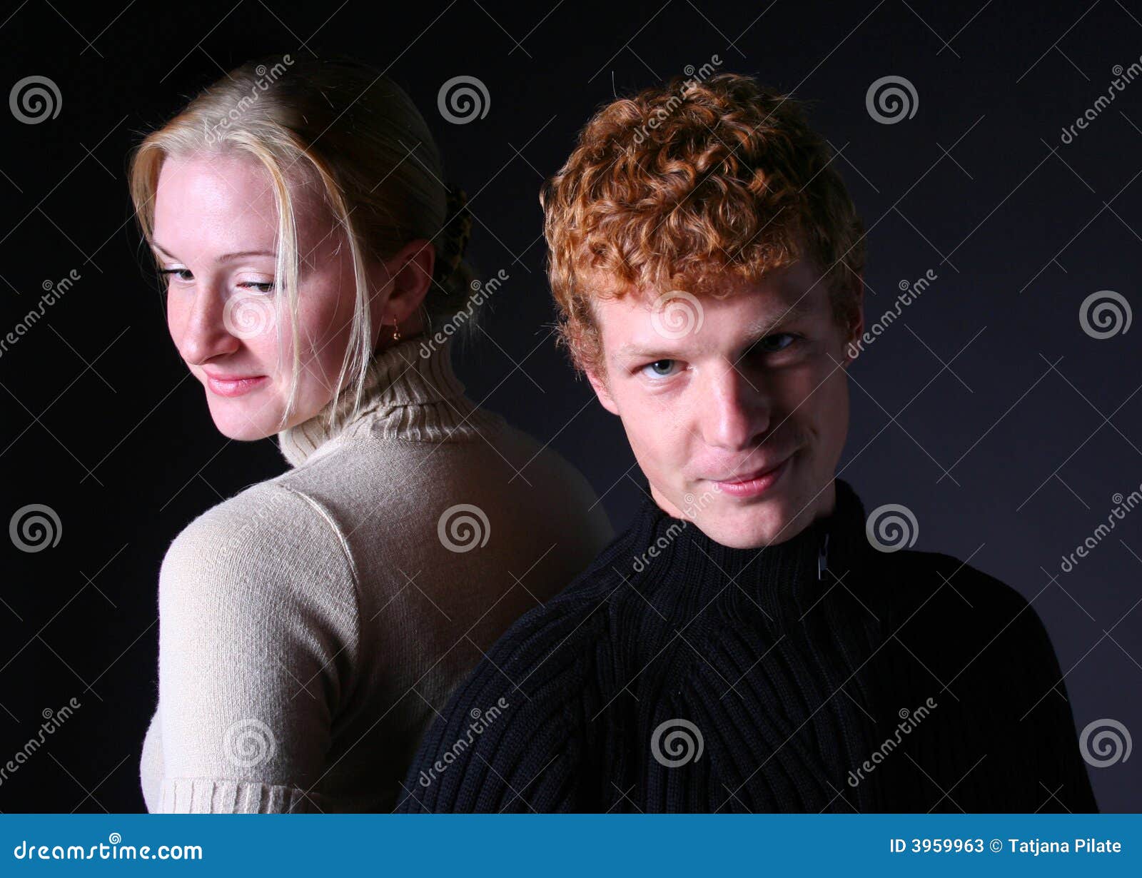 Dark. Blond girl and redhead boy on black background